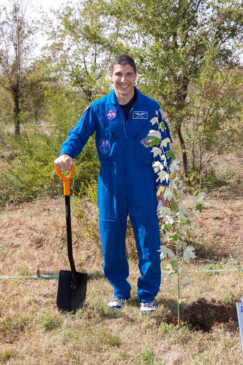 Expedition 37/38 Flight Engineer Michael Hopkins of NASA poses for photos by a tree planted in his name behind the Cosmonaut Hotel crew quarters in Baikonur, Kazakhstan Sept. 18. The tree planting was part of traditional ceremonies as  Hopkins, Kotov and Ryazanskiy prepare to launch Sept. 26, Kazakh time, from the Baikonur Cosmodrome on their Soyuz TMA-10M spacecraft for a five and a half month mission on the International Space Station.  NASA/Victor Zelentsov 