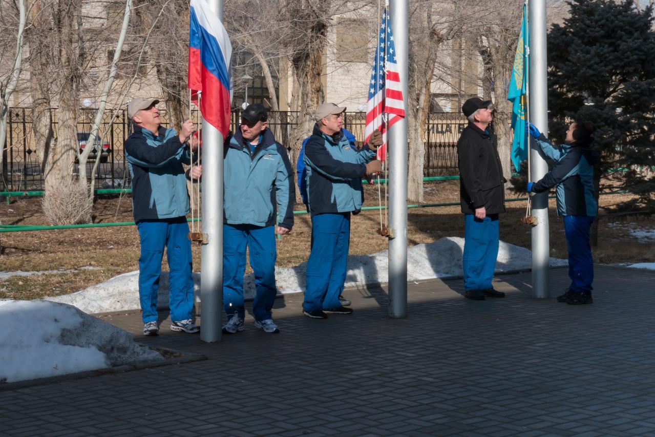 2014-03-15-11-03-34-4[1] At their Cosmonaut Hotel crew quarters in Baikonur, Kazakhstan, the Expedition 39/40 crewmembers raise the flags of Russia, the United States and Kazakhstan March 15 in traditional ceremonies that are part of the crew’s training. From left to right are Soyuz Commander Alexander Skvortsov and Flight Engineer Oleg Artemyev of the Russian Federal Space Agency (Roscosmos), Flight Engineer Steve Swanson of NASA, and backup crewmembers Alexander Samokutyaev and Elena Serova of Roscosmos. Swanson, Skvortsov and Artemyev are scheduled to launch to the International Space Station March 26 (Kazakh time) for the start of a six-month mission.  NASA/Victor Zelentsov 