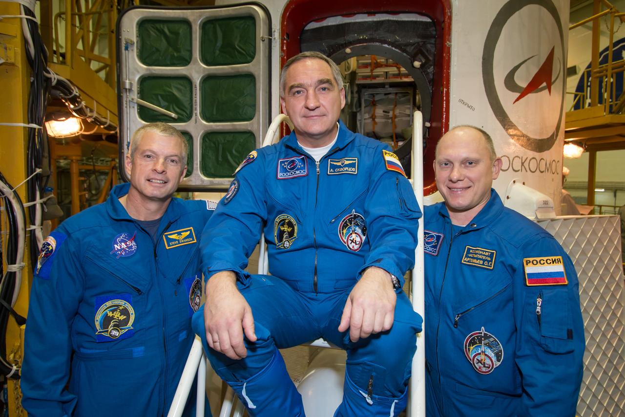 10-33-15:  In the Integration Facility at the Baikonur Cosmodrome in Kazakhstan, Expedition 39/40 Flight Engineer Steve Swanson of NASA (left), Soyuz Commander Alexander Skvortsov of the Russian Federal Space Agency (Roscosmos; center) and Flight Engineer Oleg Artemyev of Roscosmos (right) pose for pictures in front of their Soyuz TMA-12M spacecraft March 21. Swanson, Skvortsov and Artemyev are wrapping up training for their launch to the International Space Station March 26, Kazakh time, for a six-month mission on the orbital laboratory.  NASA/Victor Zelentsov 