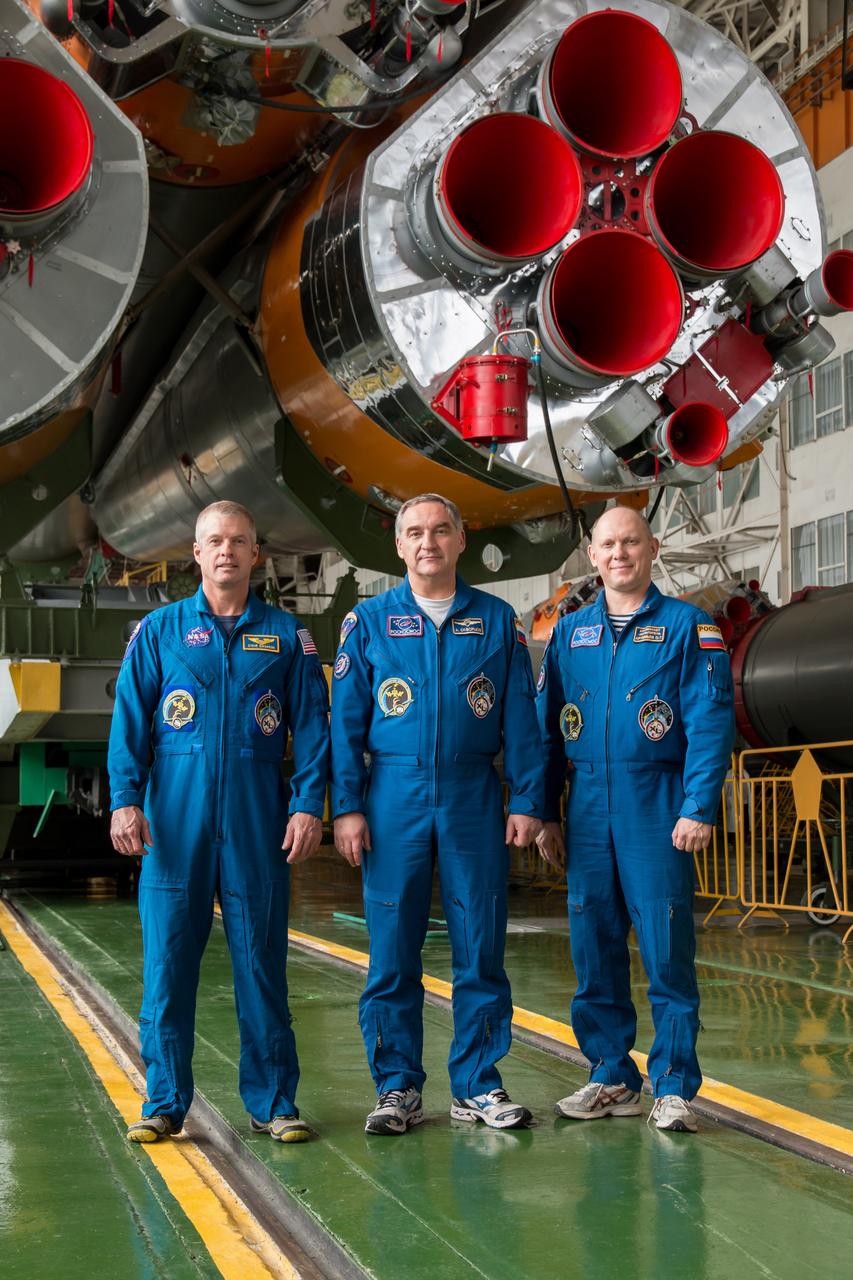12-19-17-2: In the Integration Facility at the Baikonur Cosmodrome in Kazakhstan, Expedition 39/40 Flight Engineer Steve Swanson of NASA (left), Soyuz Commander Alexander Skvortsov of the Russian Federal Space Agency (Roscosmos; center) and Flight Engineer Oleg Artemyev of Roscosmos (right) pose for pictures in front of the first stage engines of their Soyuz TMA-12M spacecraft March 21. Swanson, Skvortsov and Artemyev are wrapping up training for their launch to the International Space Station March 26, Kazakh time, for a six-month mission on the orbital laboratory. NASA/Victor Zelentsov