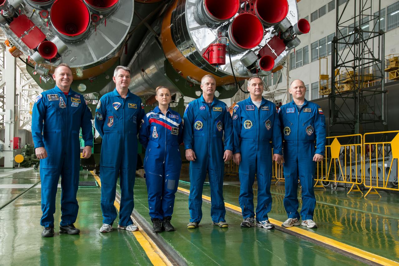 12-19-34-2:  In the Integration Facility at the Baikonur Cosmodrome in Kazakhstan, the Expedition 39/40 prime and backup crews pose for pictures in front of the first stage engines of the Soyuz TMA-12M spacecraft March 21. From left to right are backup crewmembers Barry Wilmore of NASA, Alexander Samokutyaev of the Russian Federal Space Agency (Roscosmos) and Flight Engineer Elena Serova of Roscosmos and the prime crewmembers, Flight Engineer Steve Swanson of NASA, Soyuz Commander Alexander Skvortsov of Roscosmos and Flight Engineer Oleg Artemyev of Roscosmos. Swanson, Skvortsov and Artemyev are wrapping up training for their launch to the International Space Station March 26, Kazakh time, for a six-month mission on the orbital laboratory.  NASA/Victor Zelentsov 