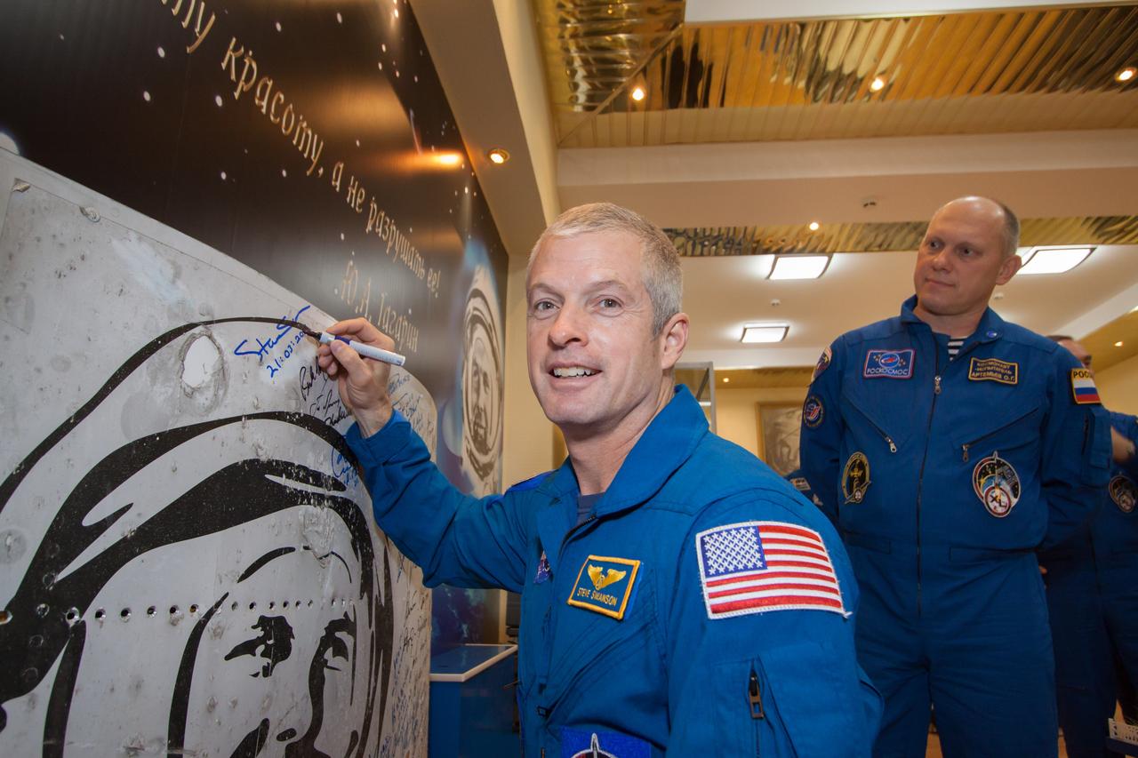 12-52-00-3:  In the Baikonur Cosmodrome Museum in Kazakhstan, Expedition 39/40 Flight Engineer Steve Swanson of NASA (foreground) signs a wall mural March 21 to honor a tradition as he and his crewmates prepare for launch  to the International Space Station. Looking on is Flight Engineer Oleg Artemyev of the Russian Federal Space Agency (Roscosmos). Swanson, Soyuz Commander Alexander Skvortsov of Roscosmos and Artemyev are wrapping up training for their launch to the station March 26, Kazakh time, on the Soyuz TMA-12 spacecraft for a six-month mission on the orbital laboratory.  NASA/Victor Zelentsov 
