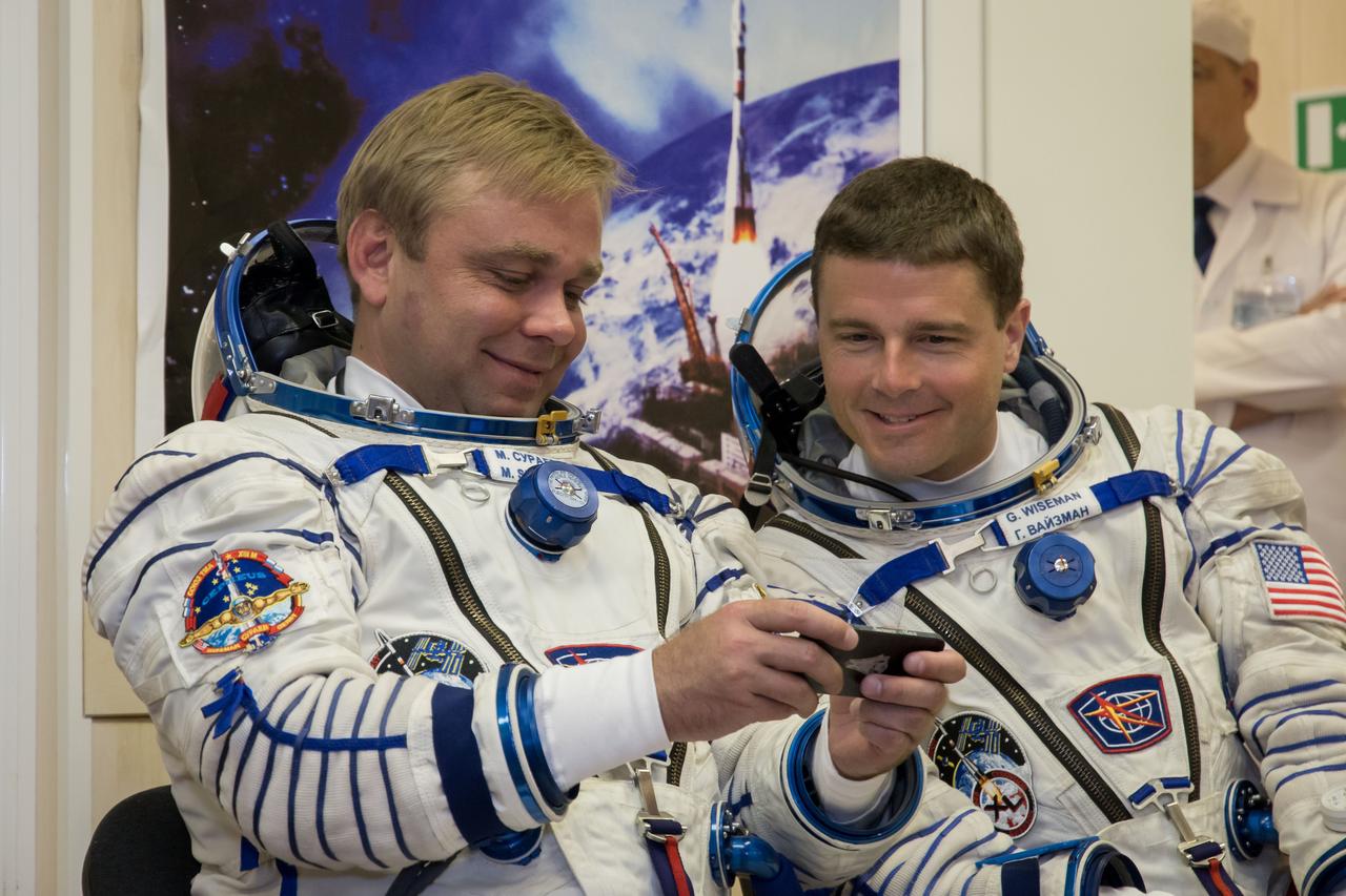 12-37-47-2: At the Baikonur Cosmodrome in Kazakhstan, Expedition 40/41 Soyuz Commander Max Suraev of the Russian Federal Space Agency (Roscosmos, left) and NASA Flight Engineer Reid Wiseman (right) look at pictures of their families on a smartphone May 16 prior to a dress rehearsal “fit check” in their Soyuz TMA-13M spacecraft. Suraev, Wiseman and Flight Engineer Alexander Gerst of the European Space Agency will launch from Baikonur on May 29, Kazakh time, in the Soyuz TMA-13M spacecraft for a 5 ½ month mission on the International Space Station. NASA/Victor Zelentsov