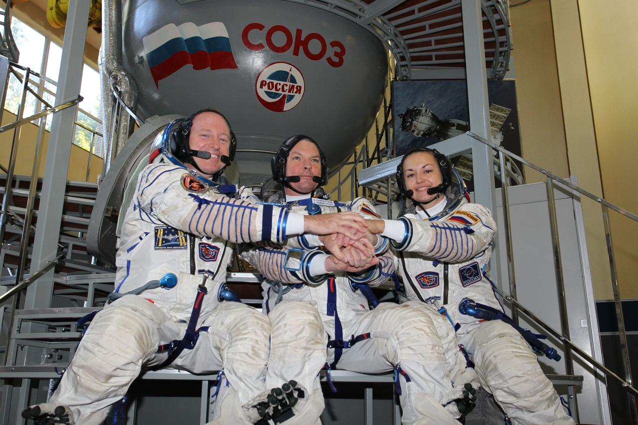 2094:  At the Gagarin Cosmonaut Training Center in Star City, Russia, Expedition 41/42 prime crewmembers Barry Wilmore of NASA (left), Alexander Samokutyaev of the Russian Federal Space Agency (Roscosmos, center) and Elena Serova of Roscosmos (right) clasp hands during a photo opportunity September 4 at the start of the second day of final qualification exams. The trio will launch from the Baikonur Cosmodrome in Kazakhstan, Sept. 26, Kazakh time, in their Soyuz TMA-14M spacecraft for a 5 ½ month mission on the International Space Station. Serova will become the fourth Russian woman to fly in space and the first Russian woman to conduct a long duration mission on the station.  NASA/Stephanie Stoll 