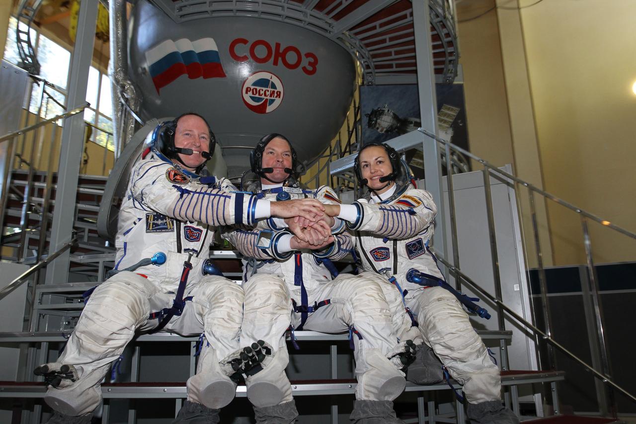 2097:  At the Gagarin Cosmonaut Training Center in Star City, Russia, Expedition 41/42 prime crewmembers Barry Wilmore of NASA (left), Alexander Samokutyaev of the Russian Federal Space Agency (Roscosmos, center) and Elena Serova of Roscosmos (right) clasp hands during a photo opportunity September 4 at the start of the second day of final qualification exams. The trio will launch from the Baikonur Cosmodrome in Kazakhstan, Sept. 26, Kazakh time, in their Soyuz TMA-14M spacecraft for a 5 ½ month mission on the International Space Station. Serova will become the fourth Russian woman to fly in space and the first Russian woman to conduct a long duration mission on the station.  NASA/Stephanie Stoll 