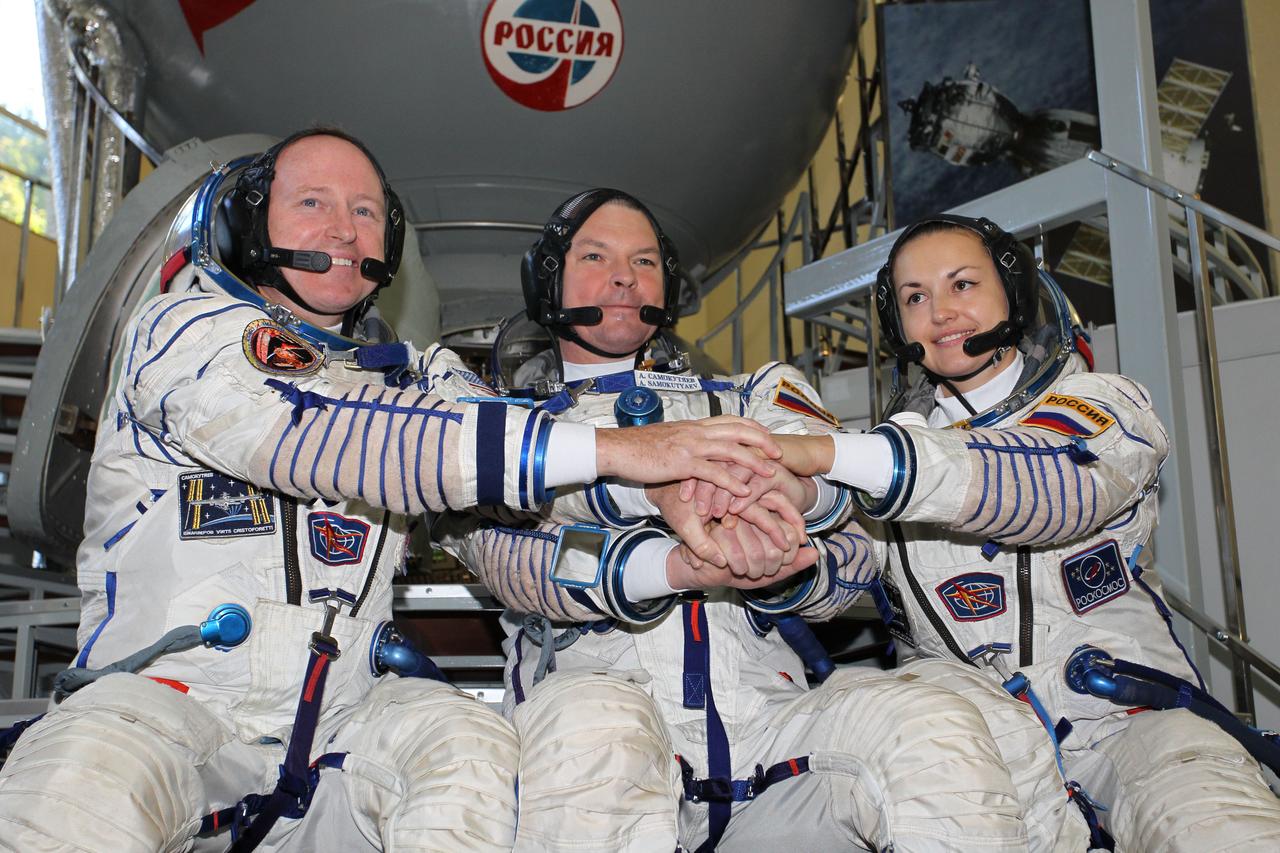 2102:  At the Gagarin Cosmonaut Training Center in Star City, Russia, Expedition 41/42 prime crewmembers Barry Wilmore of NASA (left), Alexander Samokutyaev of the Russian Federal Space Agency (Roscosmos, center) and Elena Serova of Roscosmos (right) clasp hands during a photo opportunity September 4 at the start of the second day of final qualification exams. The trio will launch from the Baikonur Cosmodrome in Kazakhstan, Sept. 26, Kazakh time, in their Soyuz TMA-14M spacecraft for a 5 ½ month mission on the International Space Station. Serova will become the fourth Russian woman to fly in space and the first Russian woman to conduct a long duration mission on the station.  NASA/Stephanie Stoll 