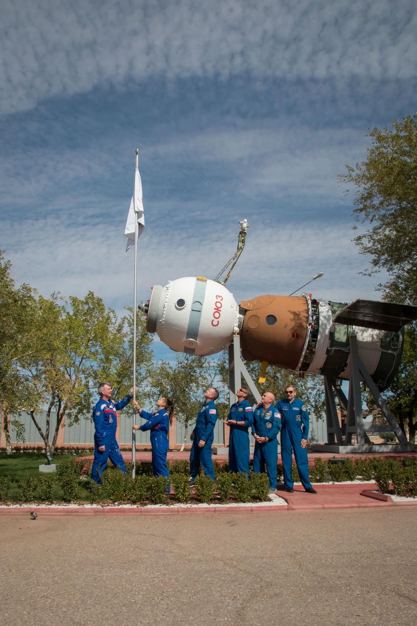 2014-09-21-14-00-27-2 Outside the Korolev Museum at the Baikonur Cosmodrome in Kazakhstan, the Expedition 41/42 prime and backup crews participate in the raising of the flag bearing their crew insignia Sept. 21 during ceremonial pre-flight activities. From left to right are prime crewmembers Alexander Samokutyaev of the Russian Federal Space Agency (Roscosmos), Elena Serova of Roscosmos and Barry Wilmore of NASA and backup crewmembers Gennady Padalka of Roscosmos, Scott Kelly of NASA and Mikhail Kornienko of Roscosmos. Wilmore, Samokutyaev and Serova will launch on Sept. 26, Kazakh time, in the Soyuz to begin a 5 ½ month mission on the International Space Station. Serova will become the fourth Russian woman to fly in space and the first to live and work on the station. Kelly and Kornienko will launch in March 2015 to spend a full year on the station. NASA/Victor Zelentsov