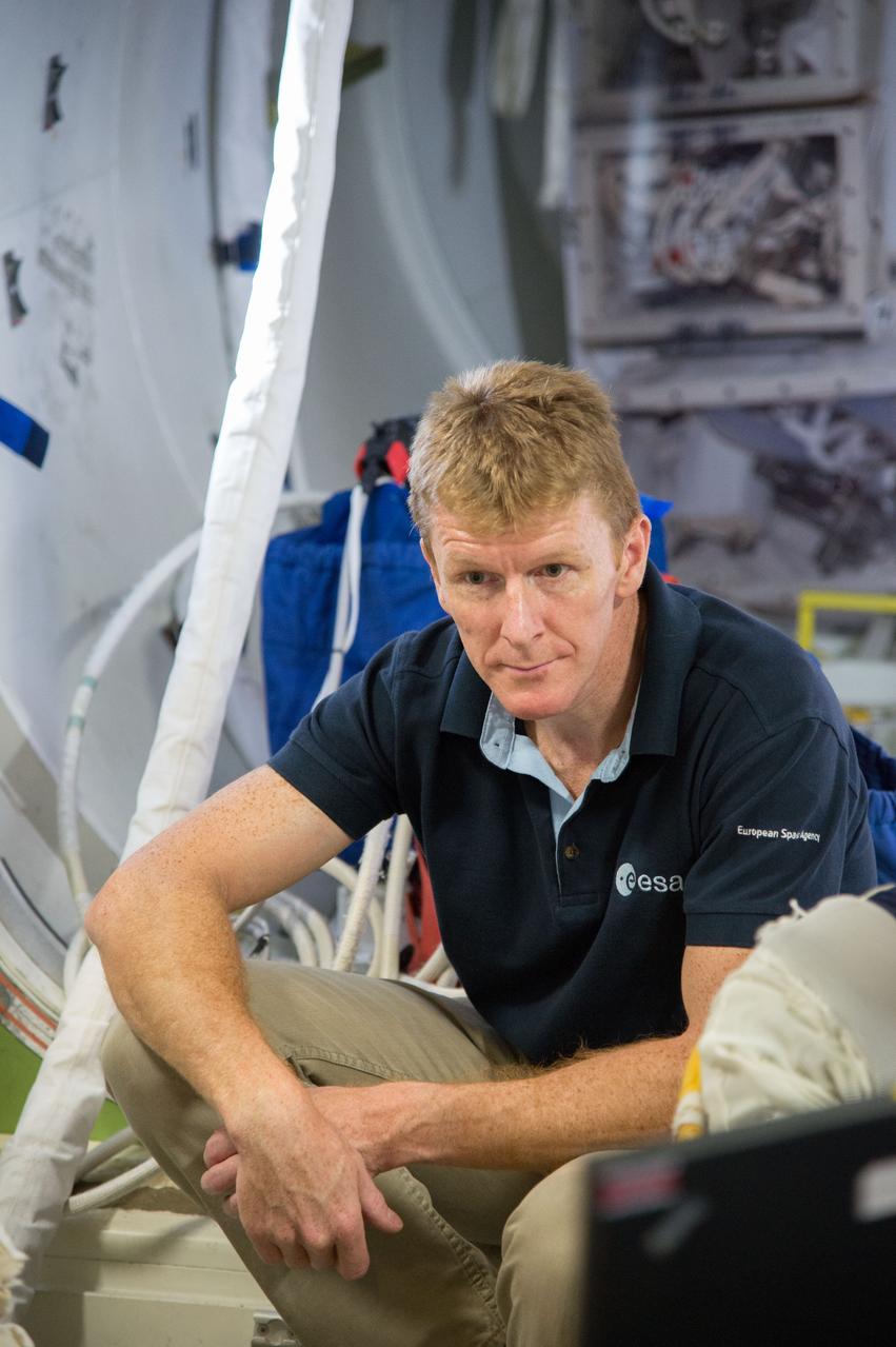 Expedition 47 ESA crewmember Tim Peake aiding fellow astronauts Expedition 48 crew member (Soyuz 46) Jeff Williams and CSA astronaut David Saint-Jacques during ISS EVA P/P training in Space Vehicle Mockup Training Facility (SVMTF) ISS Airlock mockup with instructor Megan Murphey. Photo Date: September 23, 2014. Location: Building 9NW, ISS Airlock. Photographer: Robert Markowitz