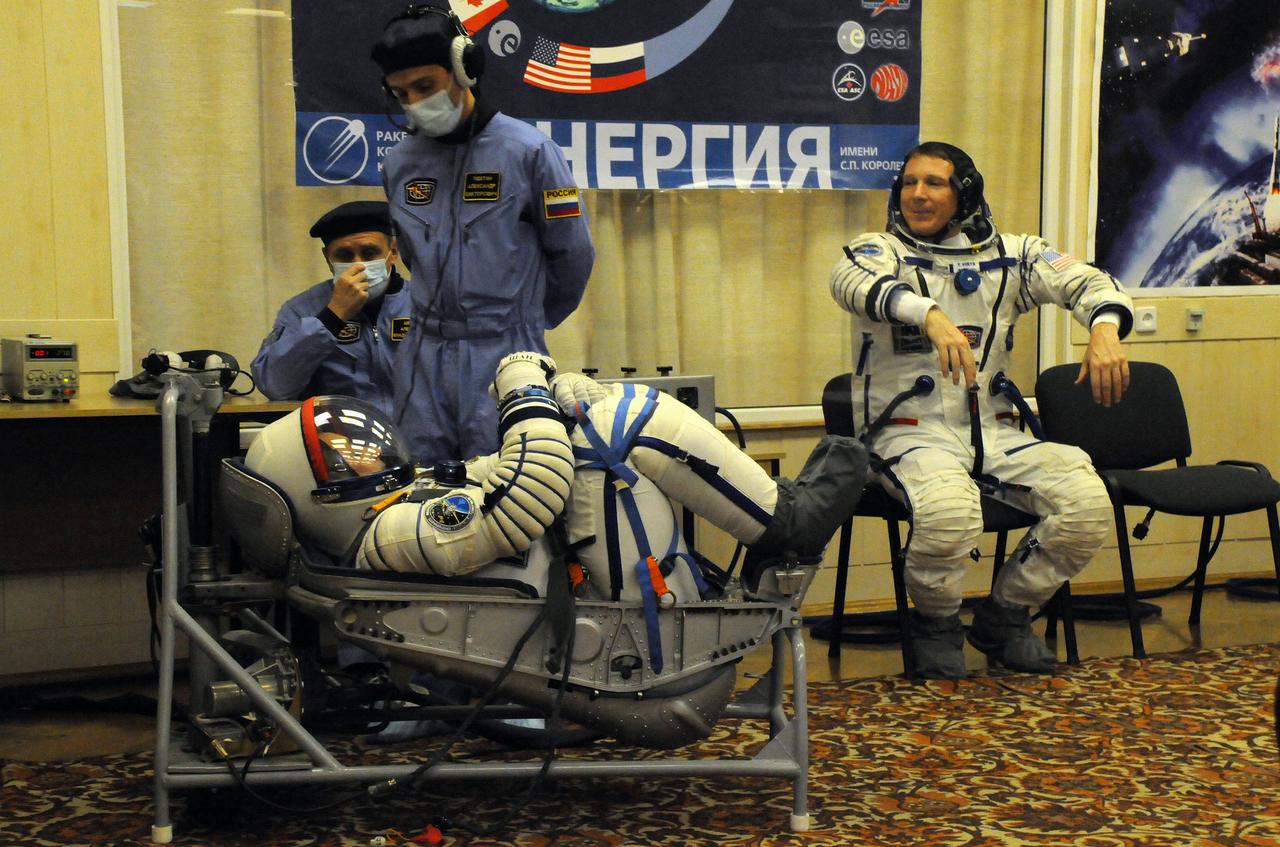 5379:  In the Integration Facility at the Baikonur Cosmodrome in Kazakhstan, Expedition 42/43 crewmember Anton Shkaplerov of the Russian Federal Space Agency (Roscosmos, left) undergoes a leak check in his Sokol launch and entry suit Nov. 12 as part of a “fit check” dress rehearsal while crewmate Terry Virts of NASA (right) gestures while waiting his turn. Shkaplerov, Virts and Samantha Cristoforetti of the European Space Agency will launch Nov. 24, Kazakh time, from Baikonur in the Soyuz TMA-15M spacecraft for a 5 ½ month mission on the International Space Station.  NASA/Victor Ivanov 