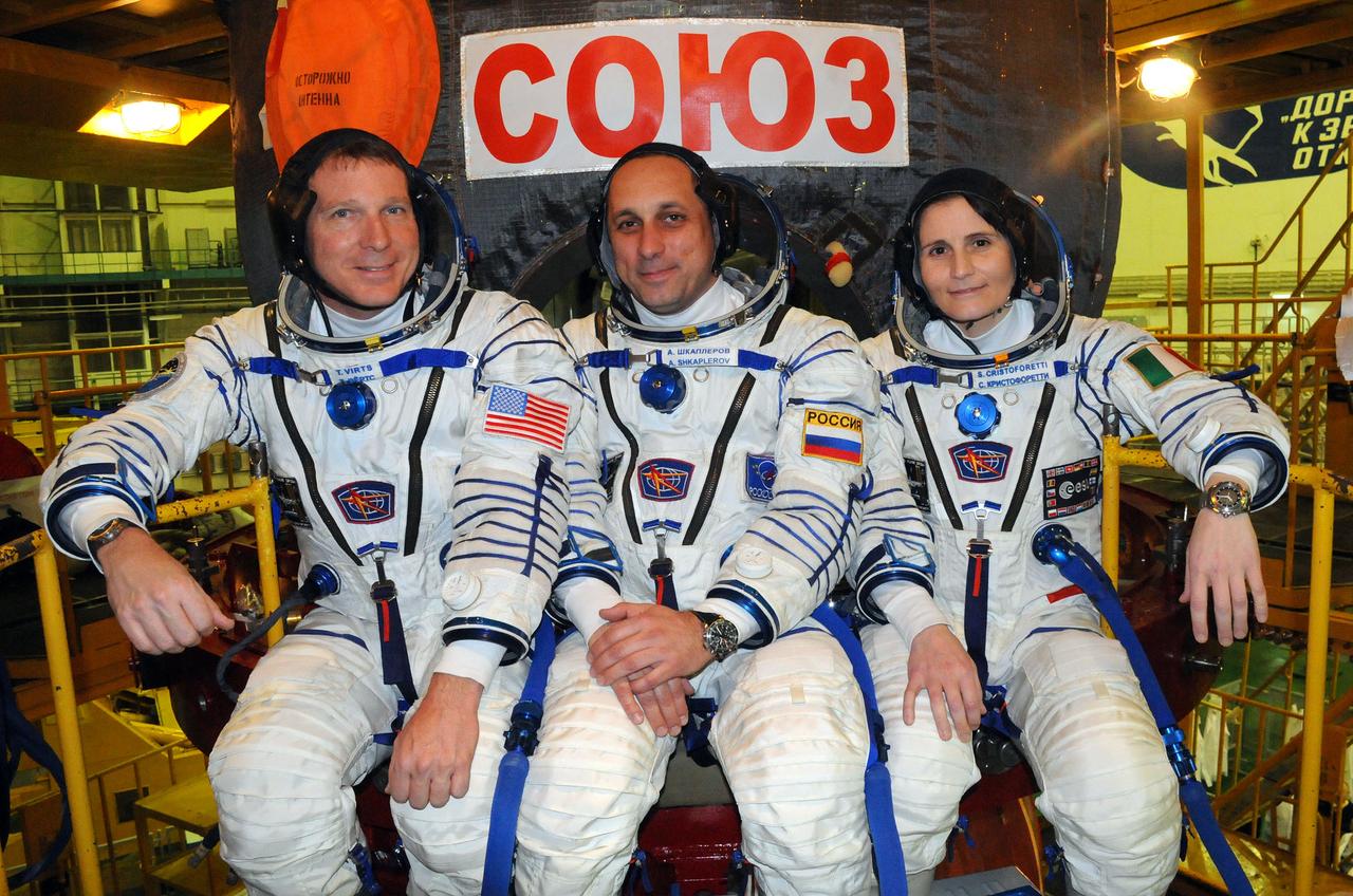 5505:  In the Integration Facility at the Baikonur Cosmodrome in Kazakhstan, Expedition 42/43 crewmembers Terry Virts of NASA (left), Anton Shkaplerov of the Russian Federal Space Agency (Roscosmos, center) and Samantha Cristoforetti of the European Space Agency (right) pose for pictures Nov. 12 in front of their Soyuz TMA-15M spacecraft during a “fit check” dress rehearsal. The trio will launch Nov. 24, Kazakh time, from Baikonur for a 5 ½ month mission on the International Space Station.  NASA/Victor Ivanov 