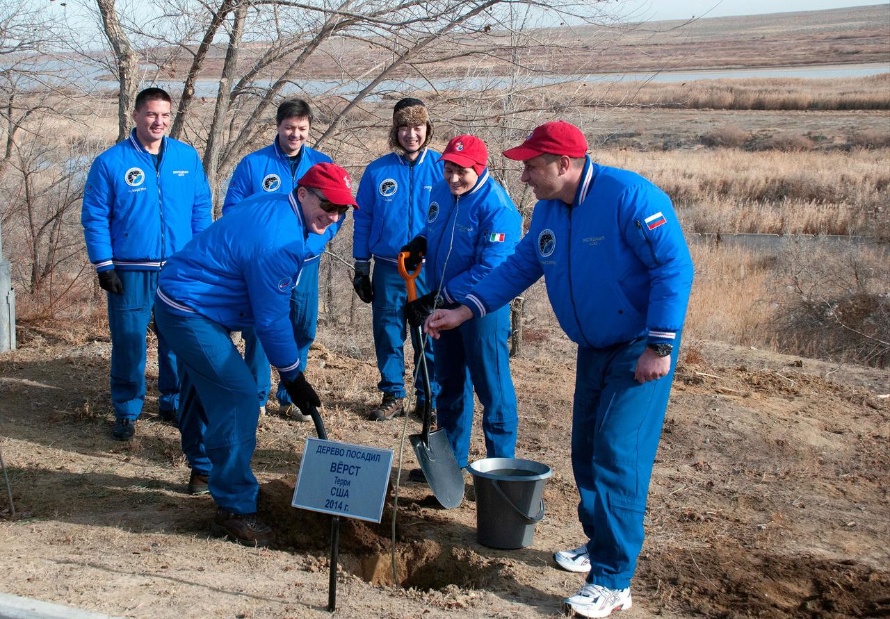6219:  Behind the Cosmonaut Hotel crew quarters in Baikonur, Kazakhstan, Expedition 42/43 crewmember Terry Virts of NASA (foreground, left) plants a tree bearing his name in traditional ceremonies Nov. 18. Looking on are crewmates Samantha Cristoforetti of the European Space Agency (center) and Anton Shkaplerov of the Russian Federal Space Agency (Roscosmos, right). In the background are backup crewmembers Kjell Lindgren of NASA, Oleg Kononenko of Roscosmos and Kimiya Yui of the Japan Aerospace Exploration Agency. Virts, Cristoforetti and Shkaplerov will launch Nov. 24, Kazakh time, from the Baikonur Cosmodrome in the Soyuz TMA-15M spacecraft for a 5 ½ month mission on the International Space Station.  NASA/Sergei Fyodorov 