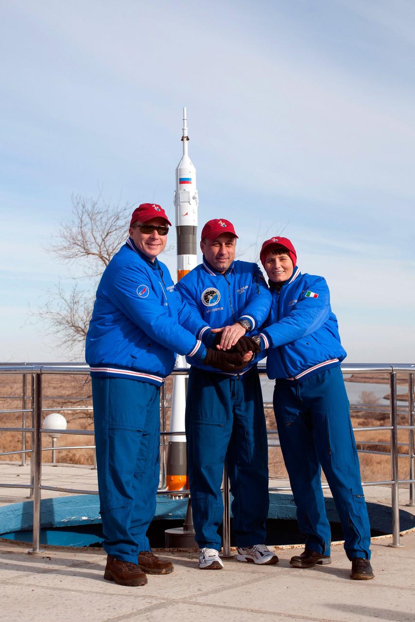6270:  Behind the Cosmonaut Hotel crew quarters in Baikonur, Kazakhstan, Expedition 42/43 crewmembers Terry Virts of NASA (left), Anton Shkaplerov of the Russian Federal Space Agency (Roscosmos, center) and Samantha Cristoforetti of the European Space Agency (right) clasp hands as they pose for pictures Nov. 18 near the end of their pre-flight training. Virts, Cristoforetti and Shkaplerov will launch Nov. 24, Kazakh time, from the Baikonur Cosmodrome in the Soyuz TMA-15M spacecraft for a 5 ½ month mission on the International Space Station.  NASA/Sergei Fyodorov 