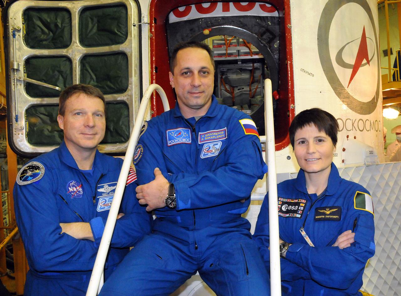 6374:  In the Integration Facility at the Baikonur Cosmodrome in Kazakhstan, Expedition 42/43 crewmembers Terry Virts of NASA (left), Anton Shkaplerov of the Russian Federal Space Agency (Roscosmos, center) and Samantha Cristoforetti of the European Space Agency (right) pose for pictures Nov. 19 in front of their Soyuz TMA-15M spacecraft during their second and final pre-launch “fit check” dress rehearsal activities. The trio will launch on Nov. 24, Kazakh time, from Baikonur for a 5 ½ month mission on the International Space Station.  NASA/Viktor Ivanov 