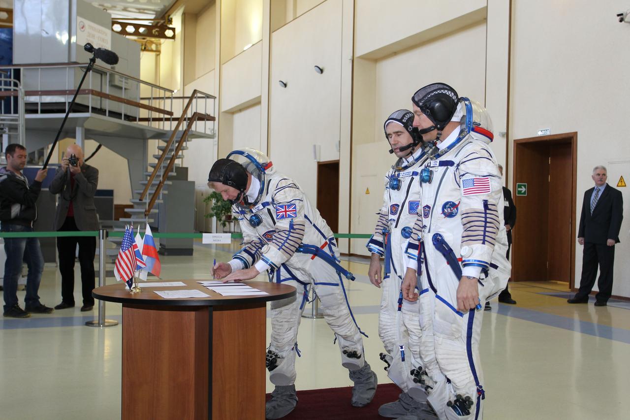 CG4G8732 --- (6 May 2015) --- At the Gagarin Cosmonaut Training Center in Star City, Russia, Expedition 44/45 backup Flight Engineer Timothy Peake of the European Space Agency signs in for the first of two days of qualification exams May 6 as his crewmates, Yuri Malenchenko of the Russian Federal Space Agency (Roscosmos, center) and Timothy Kopra of NASA (right) look on. They are the backups to the prime crew --- Kjell Lindgren of NASA, Oleg Kononenko of Roscosmos and Kimya Yui of the Japan Aerospace Exploration Agency --- who are in the final stages of training for launch May 27, Kazakh time, in the Soyuz TMA-17M spacecraft to begin a five and a half month mission to the International Space Station. Photo credit: NASA/Seth Marcantel