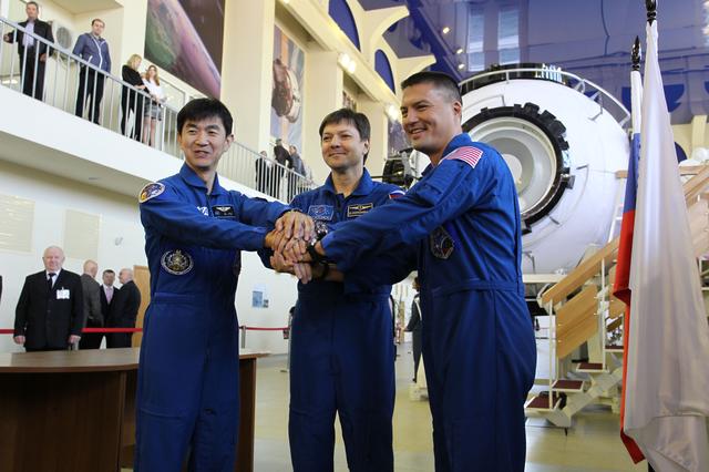 NASA image: CG4G9064 --- (6 May 2015) --- At the Gagarin Cosmonaut Training Center in Star City, Russia, Expedition 44/45 crewmembers Kimya Yui of the Japan Aerospace Exploration Agency (left), Oleg Kononenko of the Russian Federal Space Agency (Roscosmos, center), and Kjell Lindgren of NASA (right) clasp hands for photographers on the first of two days of qualification exams May 6. The trio is preparing for launch from the Baikonur Cosmodrome in Kazakhstan on May 27, Kazakh time, in the Soyuz TMA-17M spacecraft to begin a five and a half month mission to the International Space Station. Photo credit: NASA/Seth Marcantel