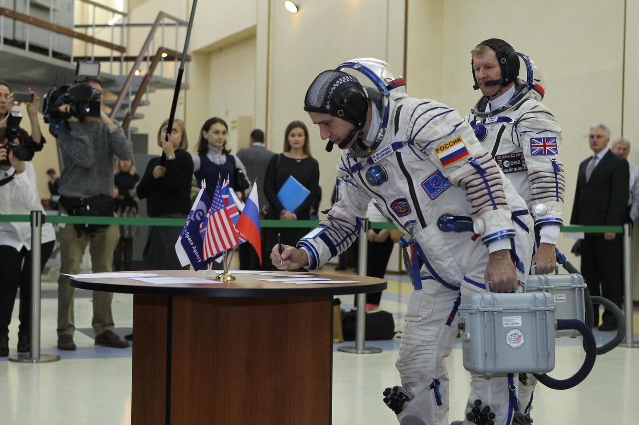 At the Gagarin Cosmonaut Training Center in Star City, Russia, Expedition 46-47 crewmember Yuri Malenchenko of the Russian Federal Space Agency (Roscosmos) signs in for his qualification exam Nov. 20 as his crewmate, Tim Peake of the European Space Agency looks on. Along with Tim Kopra of NASA, Malenchenko and Peake will launch Dec. 15 on their Soyuz TMA-19M spacecraft Dec. 15 from the Baikonur Cosmodrome in Kazakhstan for a six-month mission on the International Space Station. NASA/Seth Marcantel