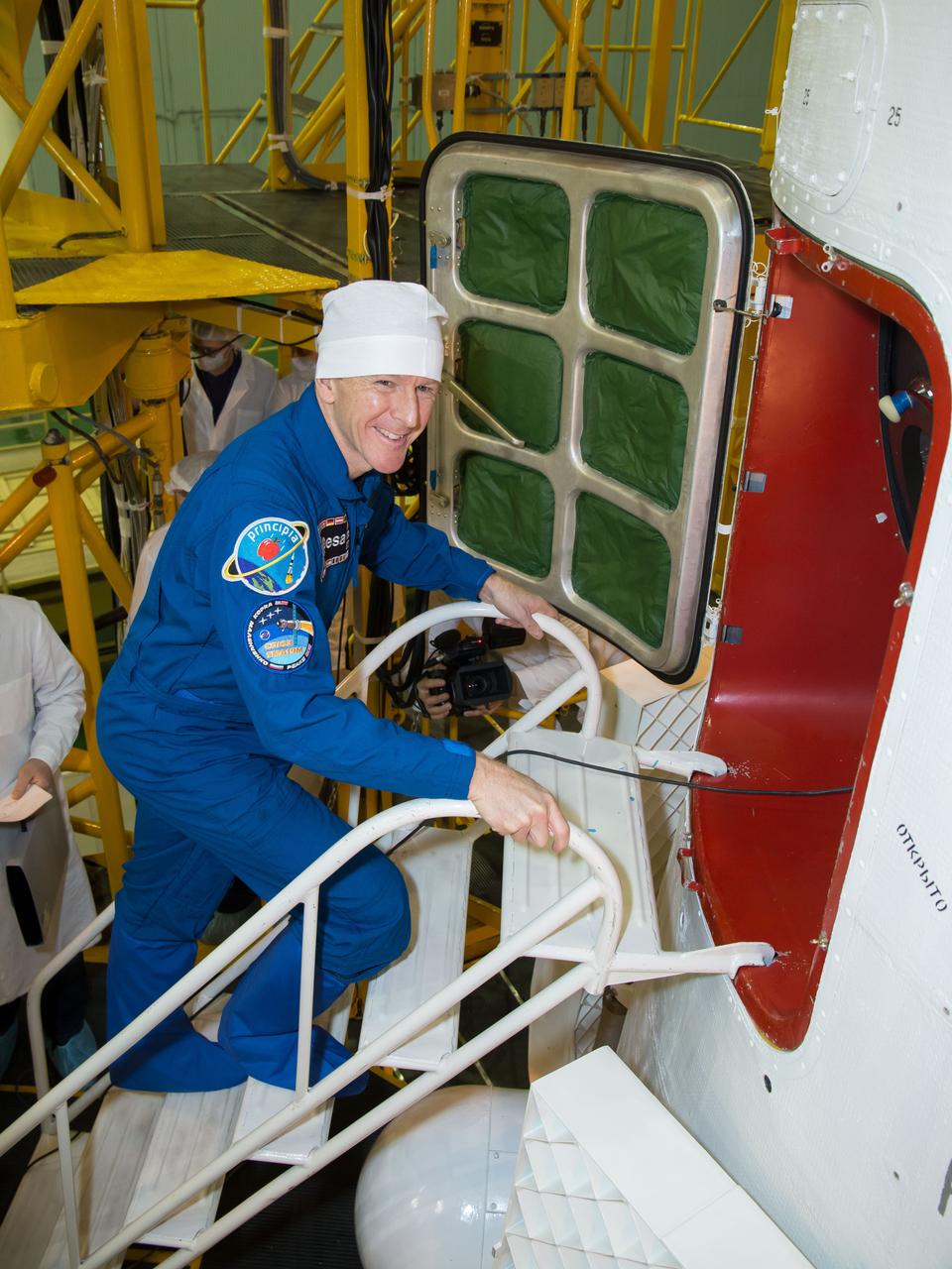 In the Integration Facility at the Baikonur Cosmodrome in Kazakhstan, Expedition 46-47 crewmember Tim Peake of the European Space Agency flashes a smile before entering his Soyuz spacecraft Dec. 10 during a final fit check and inspection. Peake, Tim Kopra of NASA and Yuri Malenchenko of the Russian Federal Space Agency (Roscosmos) will launch Dec. 15 on the Soyuz TMA-19M spacecraft for a six-month mission on the International Space Station.  NASA/Victor Zelentsov 