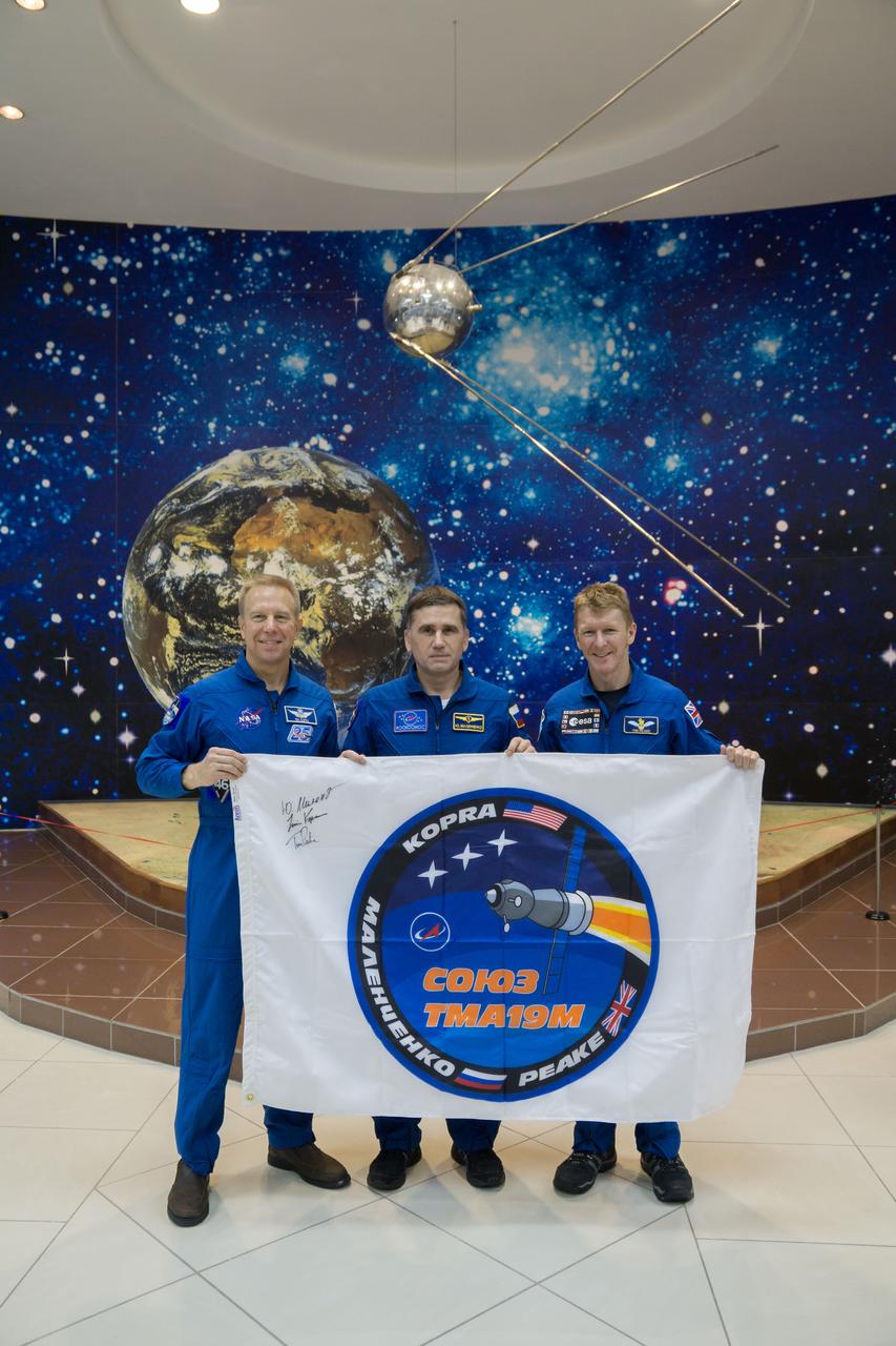 During a break from training, the Expedition 46-47 crewmembers toured the Korolev Museum at the Baikonur Cosmodrome in Kazakhstan Dec. 10 and displayed a flag bearing the logo for their Soyuz mission. From left to right are Tim Kopra of NASA,  Yuri Malenchenko of the Russian Federal Space Agency (Roscosmos) and Tim Peake of the European Space Agency. Kopra, Peake and Malenchenko will launch Dec. 15 on the Soyuz TMA-19M spacecraft for a six-month mission on the International Space Station.  NASA/Victor Zelentsov 
