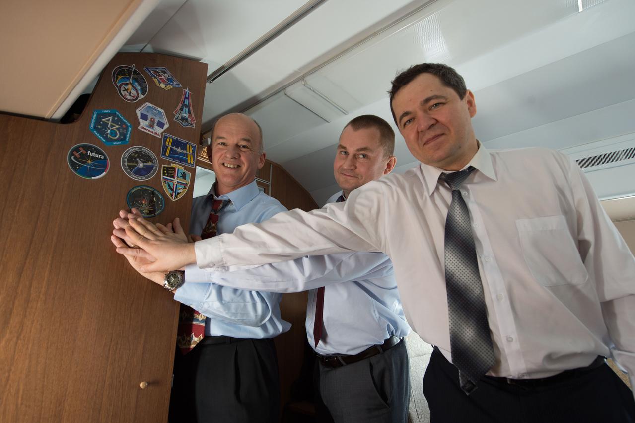 Aboard their Gagarin Cosmonaut Training Center aircraft, Expedition 47-48 crewmembers Jeff Williams of NASA (left) and Alexey Ovchinin (center) and Oleg Skripochka (right) of Roscosmos affix a sticker of their crew patch to the wall of the cabin as they flew from their training base to the Baikonur Cosmodrome in Kazakhstan March 3. The trio will launch March 19, Kazakh time, in their Soyuz TMA-20M spacecraft for a six-month mission on the International Space Station. Courtesy of Gagarin Cosmonaut Training Center