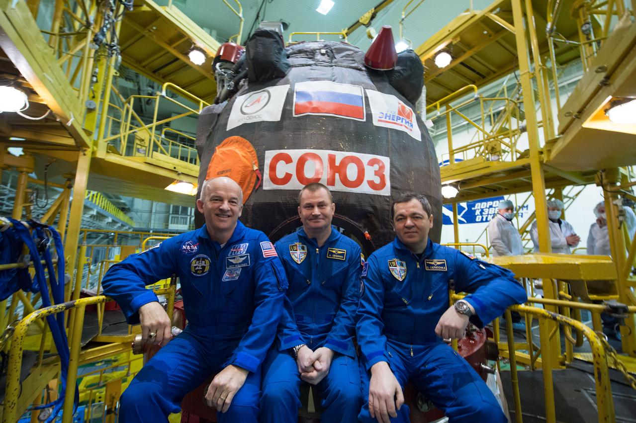 In the Integration Facility at the Baikonur Cosmodrome in Kazakhstan, Expedition 47-48 crewmembers Jeff Williams of NASA (left) and Alexey Ovchinin (center) and Oleg Skripochka (right) of Roscosmos pose for pictures March 4 in front of their Soyuz TMA-20M spacecraft during final pre-launch training. The trio will launch March 19, Kazakh time, for a six-month mission on the International Space Station. Courtesy of Gagarin Cosmonaut Training Center