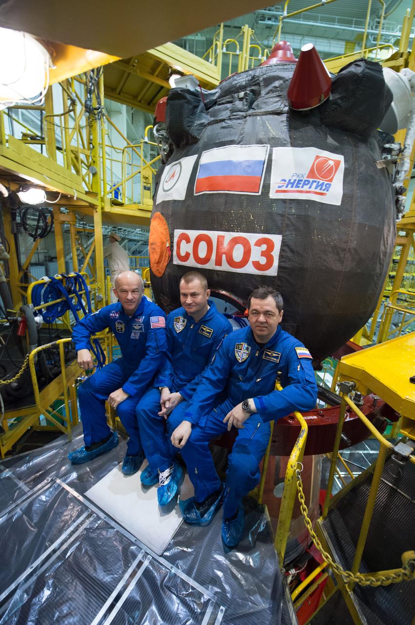 In the Integration Facility at the Baikonur Cosmodrome in Kazakhstan, Expedition 47-48 crewmembers Jeff Williams of NASA (left) and Alexey Ovchinin (center) and Oleg Skripochka (right) of Roscosmos pose for pictures March 4 in front of their Soyuz TMA-20M spacecraft during final pre-launch training. The trio will launch March 19, Kazakh time, for a six-month mission on the International Space Station. Courtesy of Gagarin Cosmonaut Training Center