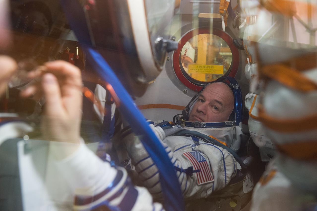 In the Integration Facility at the Baikonur Cosmodrome in Kazakhstan, Expedition 47-48 crewmember Jeff Williams of NASA is seen in his seat through a window on the Soyuz TMA-20M spacecraft March 4 as he and his crewmates conducted a “fit check” dress rehearsal during pre-launch training. Williams and Alexey Ovchinin and Oleg Skripochka of Roscosmos will launch March 19, Kazakh time, for a six-month mission on the International Space Station. Courtesy of Gagarin Cosmonaut Training Center