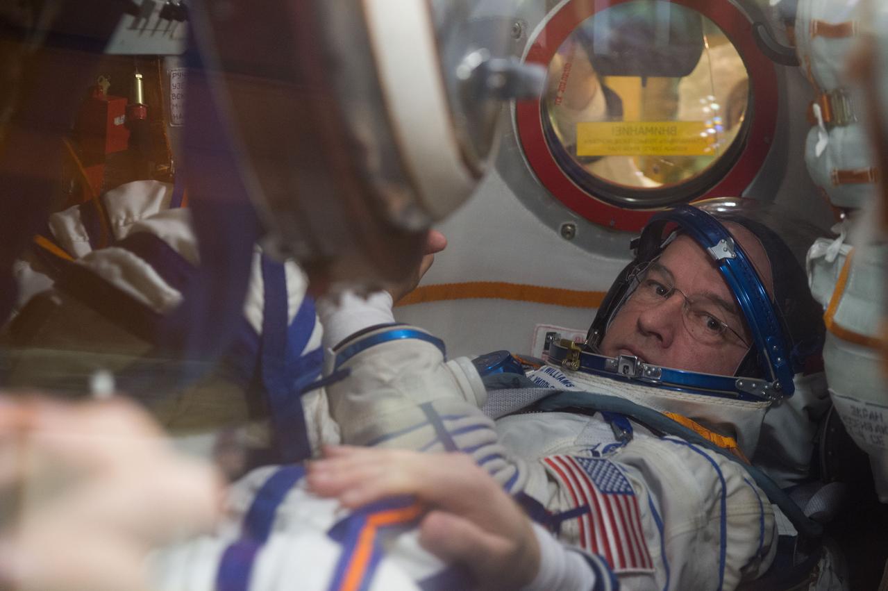 In the Integration Facility at the Baikonur Cosmodrome in Kazakhstan, Expedition 47-48 crewmember Jeff Williams of NASA is seen in his seat through a window on the Soyuz TMA-20M spacecraft March 4 as he and his crewmates conducted a “fit check” dress rehearsal during pre-launch training. Williams and Alexey Ovchinin and Oleg Skripochka of Roscosmos will launch March 19, Kazakh time, for a six-month mission on the International Space Station. Courtesy of Gagarin Cosmonaut Training Center