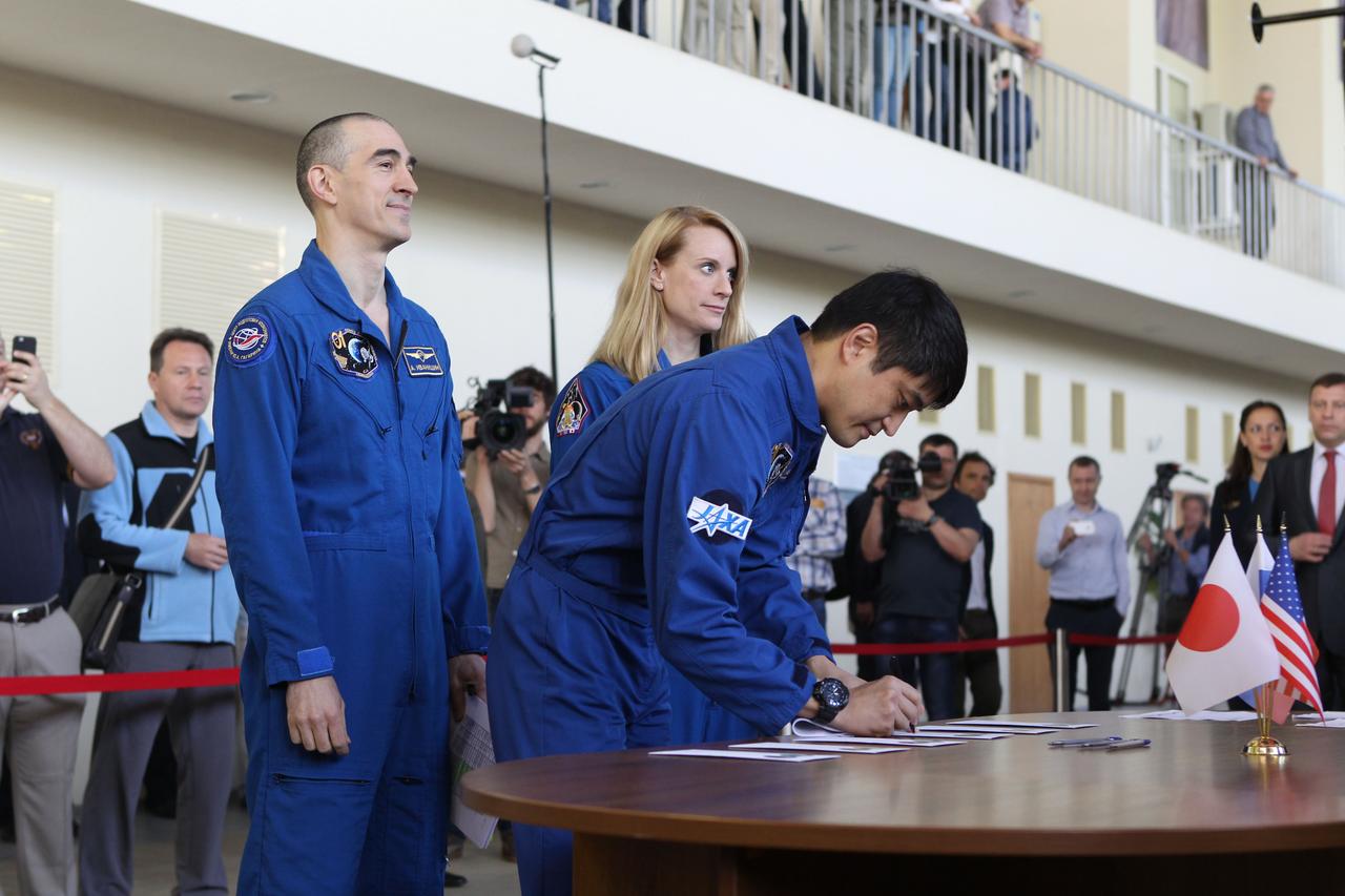 At the Gagarin Cosmonaut Training Center in Star City, Russia, Expedition 48-49 prime crewmember Takuya Onishi of the Japan Aerospace Exploration Agency signs in for the start of final qualification exams May 26 as his crewmates, Anatoly Ivanishin of Roscosmos (left) and Kate Rubins of NASA (right) look on. Rubins, Onishi and Ivanishin will launch June 24 on the Soyuz MS-01 spacecraft from the Baikonur Cosmodrome in Kazakhstan for a four-month mission on the International Space Station.  NASA/Stephanie Stoll 