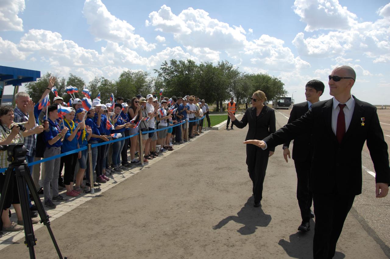 ISS Expedition 48-49 prime crewmembers Kate Rubins of NASA (left), Takuya Onishi of the Japan Aerospace Exploration Agency (center) and Anatoly Ivanishin of Roscosmos (right) wave to schoolchildren after arriving in Baikonur, Kazakhstan June 24 for final pre-launch training following a flight from Star City, Russia. The trio will launch July 7 from the Baikonur Cosmodrome in Kazakhstan on the Soyuz MS-01 spacecraft for a planned four-month mission on the International Space Station.  NASA/Alexander Vysotsky 