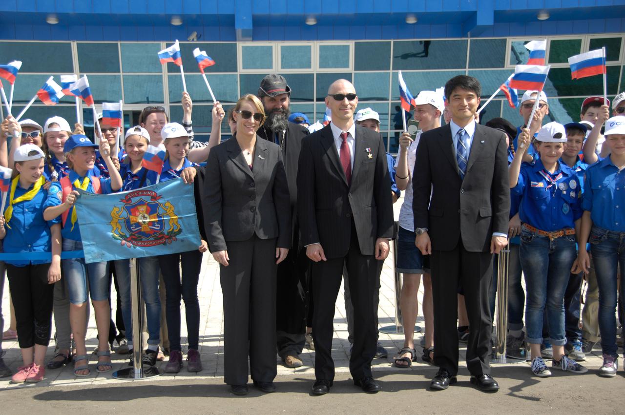 ISS Expedition 48-49 prime crewmembers Kate Rubins of NASA (left), Anatoly Ivanishin of Roscosmos (center) and Takuya Onishi of the Japan Aerospace Exploration Agency (right) pose for pictures with schoolchildren after arriving in Baikonur, Kazakhstan June 24 for final pre-launch training following a flight from Star City, Russia. The trio will launch July 7 from the Baikonur Cosmodrome in Kazakhstan on the Soyuz MS-01 spacecraft for a planned four-month mission on the International Space Station.  NASA/Alexander Vysotsky 