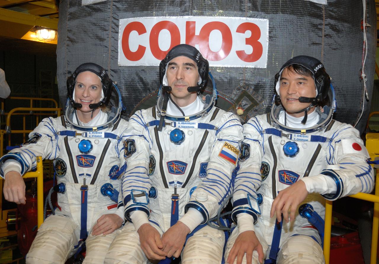 In the Integration Facility at the Baikonur Cosmodrome in Kazakhstan, Expedition 48-49 crewmembers Kate Rubins of NASA (left), Anatoly Ivanishin of Roscosmos (center) and Takuya Onishi of the Japan Aerospace Exploration Agency (right) pose for pictures June 25 in front of the Soyuz MS-01 spacecraft during a “fit check” dress rehearsal activity. The trio will launch on July 7, Baikonur time, on the Soyuz MS-01 for a planned four-month mission on the International Space Station.  NASA/Alexander Vysotsky 