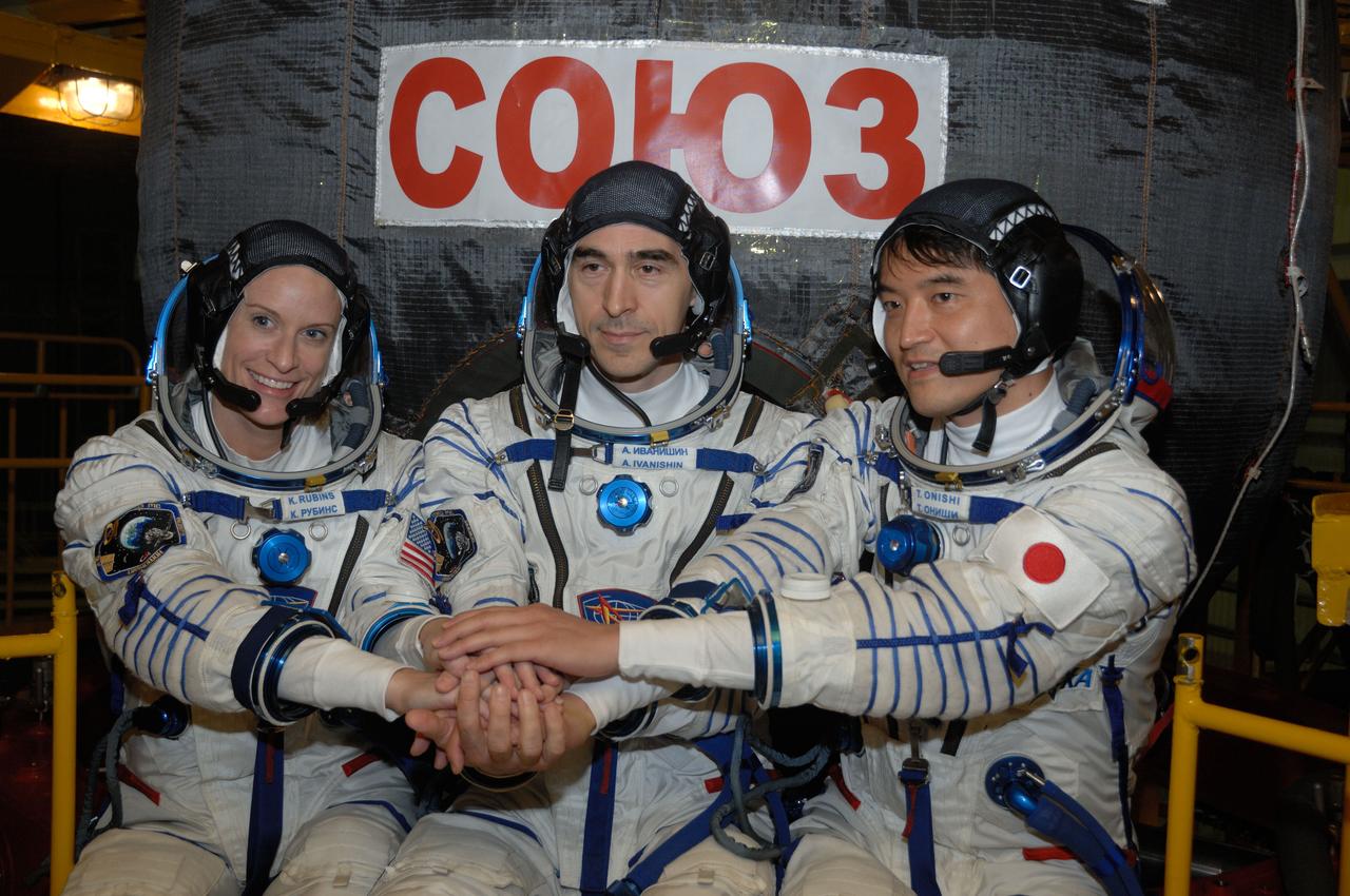 In the Integration Facility at the Baikonur Cosmodrome in Kazakhstan, Expedition 48-49 crewmembers Kate Rubins of NASA (left), Anatoly Ivanishin of Roscosmos (center) and Takuya Onishi of the Japan Aerospace Exploration Agency (right) pose for pictures June 25 in front of the Soyuz MS-01 spacecraft during a “fit check” dress rehearsal activity. The trio will launch on July 7, Baikonur time, on the Soyuz MS-01 for a planned four-month mission on the International Space Station.  NASA/Alexander Vysotsky 