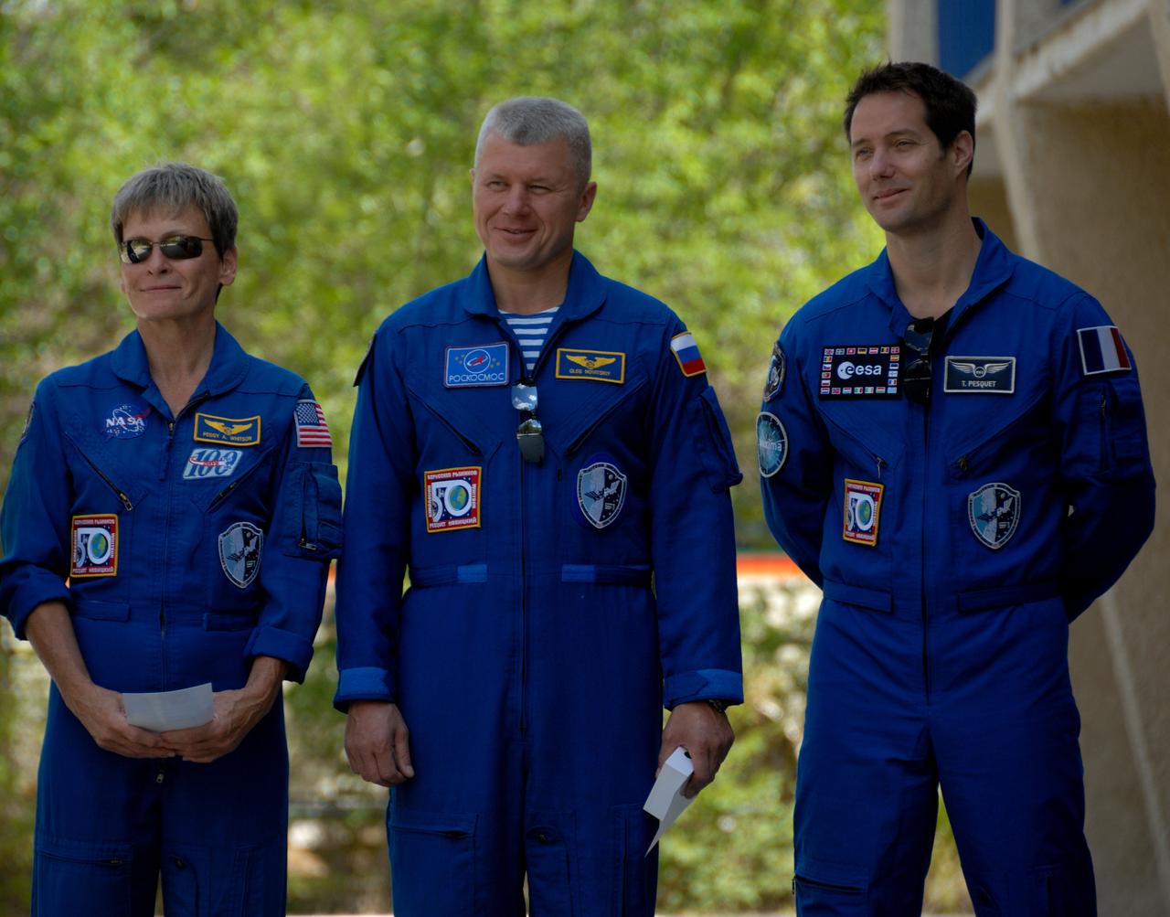 Outside their Cosmonaut Hotel crew quarters in Baikonur, Kazakhstan, Expedition 48-49 backup crewmembers Peggy Whitson of NASA (left), Oleg Novitskiy of Roscosmos (center) and Thomas Pesquet of the European Space Agency (right) listen to remarks June 26 during the traditional raising of the American, Russian, Japanese and Kazakh flags. Prime crewmembers Kate Rubins of NASA, Anatoly Ivanishin of Roscosmos and Takuya Onishi of the Japan Aerospace Exploration Agency will launch on July 7, Baikonur time, on the Soyuz MS-01 spacecraft for a planned four-month mission on the International Space Station.  NASA/Alexander Vysotsky 