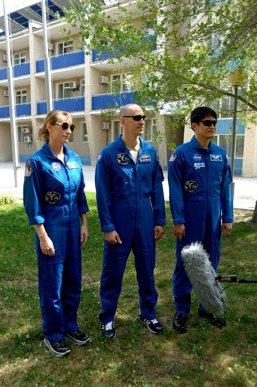 Outside their Cosmonaut Hotel crew quarters in Baikonur, Kazakhstan, Kate Rubins of NASA (left), Anatoly Ivanishin of Roscosmos (center) and Takuya Onishi of the Japan Aerospace Exploration Agency (right) answer reporters’ questions June 26 as they continue preparations for launch on July 7, Baikonur time, on the Soyuz MS-01 spacecraft for a planned four-month mission on the International Space Station.  NASA/Alexander Vysotsky 