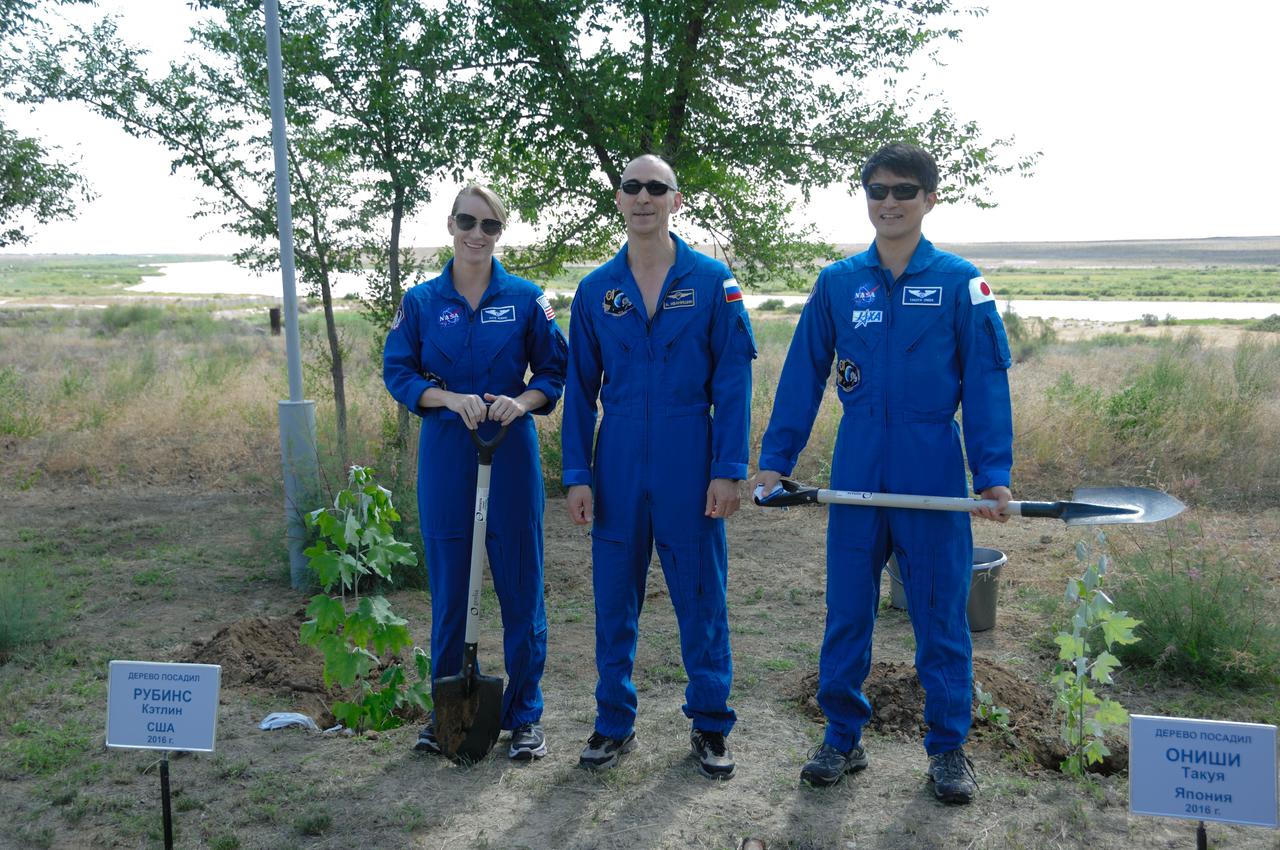 At the Cosmonaut Hotel in Baikonur, Kazakhstan, Expedition 48-49 crewmembers Kate Rubins of NASA (left), Anatoly Ivanishin of Roscosmos (center) and Takuya Onishi of the Japan Aerospace Exploration Agency (right) pose for pictures June 30 after Rubins and Onishi, both first-time fliers, planted trees in their names in traditional pre-launch activities. Rubins, Ivanishin and Onishi will launch July 7, Baikonur time, on the Soyuz MS-01 spacecraft for a planned four-month mission on the International Space Station.  NASA/Alexander Vysotsky 
