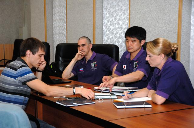 NASA image: At the Cosmonaut Hotel in Baikonur, Kazakhstan, Expedition 48-49 crewmembers Anatoly Ivanishin of Roscosmos (second from left), Takuya Onishi of the Japan Aerospace Exploration Agency (second from right) and Kate Rubins of NASA (far right) listen to a rendezvous instructor June 30 during pre-launch training. Rubins, Ivanishin and Onishi will launch July 7, Baikonur time, on the Soyuz MS-01 spacecraft for a planned four-month mission on the International Space Station...NASA/Alexander Vysotsky.