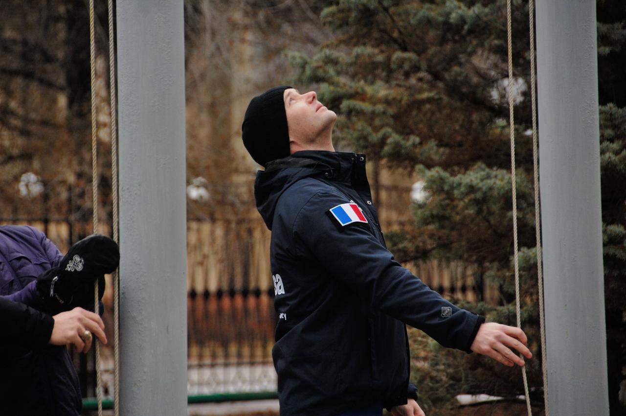 Under leaden skies outside the Cosmonaut Hotel crew quarters in Baikonur, Kazakhstan, Expedition 50 crewmember Thomas Pesquet of the European Space Agency raises the flag of France Nov. 3 during a traditional ceremony. Peggy Whitson of NASA, Oleg Novistkiy of the Russian Federal Space Agency (Roscosmos) and Pesquet will launch Nov. 18, Baikonur time, on the Soyuz MS-03 spacecraft for a six-month mission on the International Space Station.  NASA/Alexander Vysotsky 