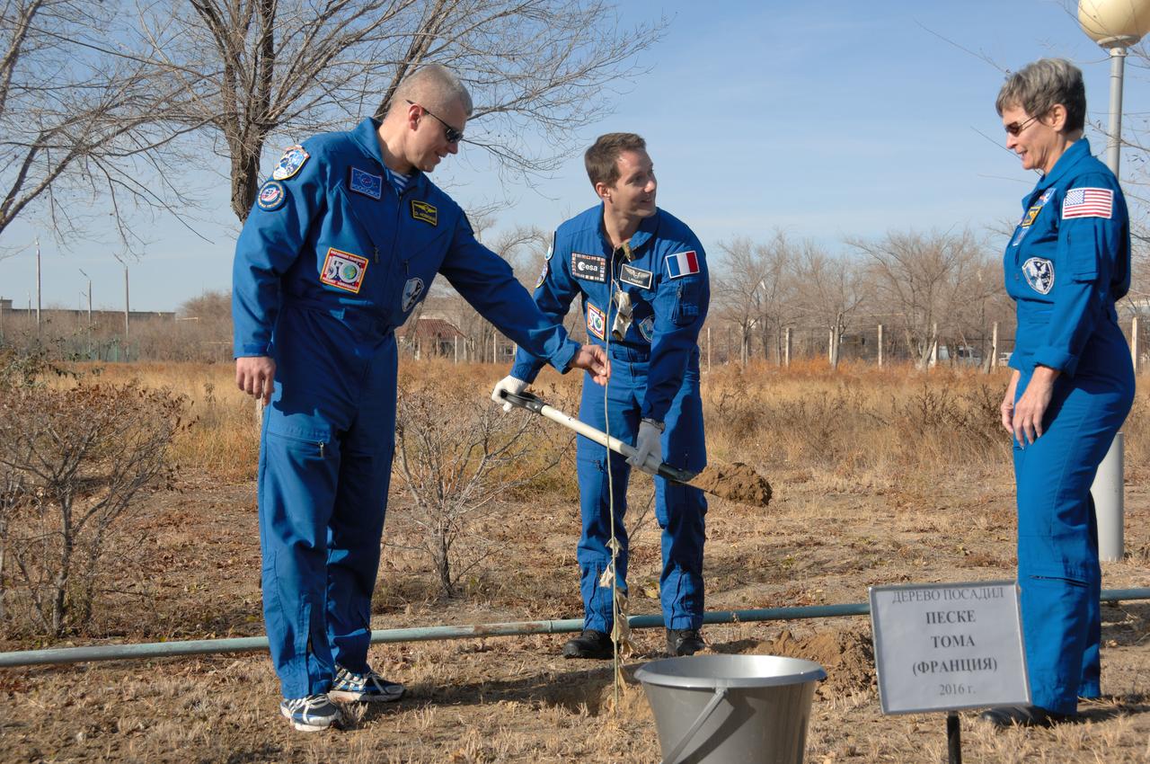 At the Cosmonaut Hotel crew quarters in Baikonur, Kazakhstan, Expedition 50-51 crewmember Thomas Pesquet of the European Space Agency (center) plants a tree bearing his name in traditional ceremonies Nov. 10 as his crewmates, Oleg Novitskiy of the Russian Federal Space Agency (Roscosmos, left) and Peggy Whitson of NASA (right) look on. They will launch Nov. 18, Baikonur time, on the Soyuz MS-03 spacecraft for a six-month mission on the International Space Station. NASA/Alexander Vysotsky