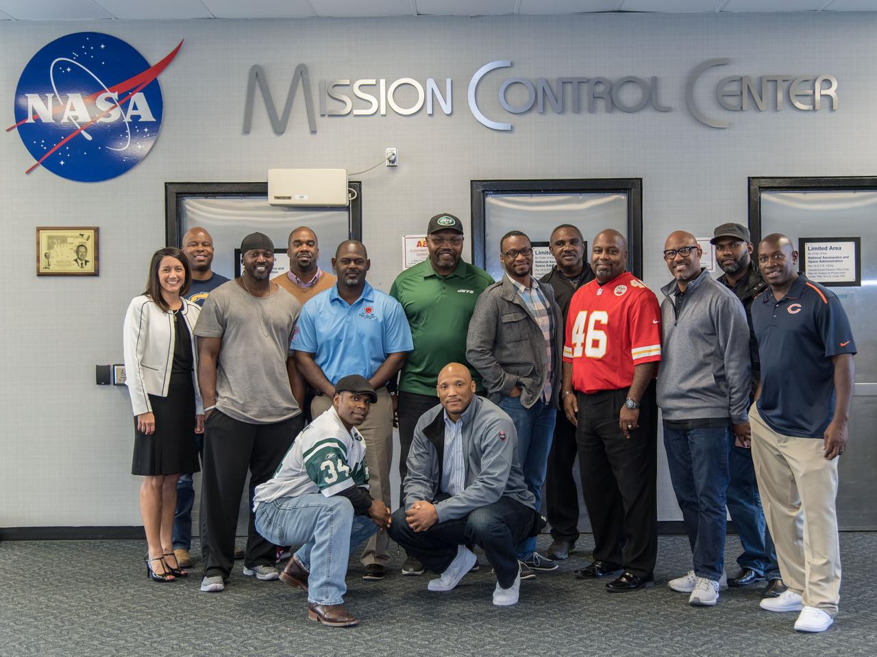 jsc2017e009735 (01/26/2017) --- Former NFL players on tour of the Johnson Space Center (JSC) as part of the Centers Super Bowl tailgate event gathered together in front of JSC's Mission Control. The former players toured JSC in the week before the Super Bowl game. Kneeling front left: Kerry Henderson (NY Jets), Joe Wesley (49ers, Jaguars), First standing row, left: Ronald Humphrey (IN Colts), James Williams (Saints, Jag, 49ers, Browns), Emanuel McNeil (NY Jets), Sammy Davis (Chargers, 49ers, Buccaneers), Daryl Gaines (KC Chiefs, Cris Calloway (Giants, Steelers, Falcons, Patriots), Lemanual Stinson (Bears & Falcons). Back row left: Ginger Kerrrick (JSC Staff), Jermaine Fazonde (Chargers), Michael Holmes (49ers), Kevin Williams (Vikings, Seahawks, Saints). NASA PHOTOGRAPHER: Lauren Harnett