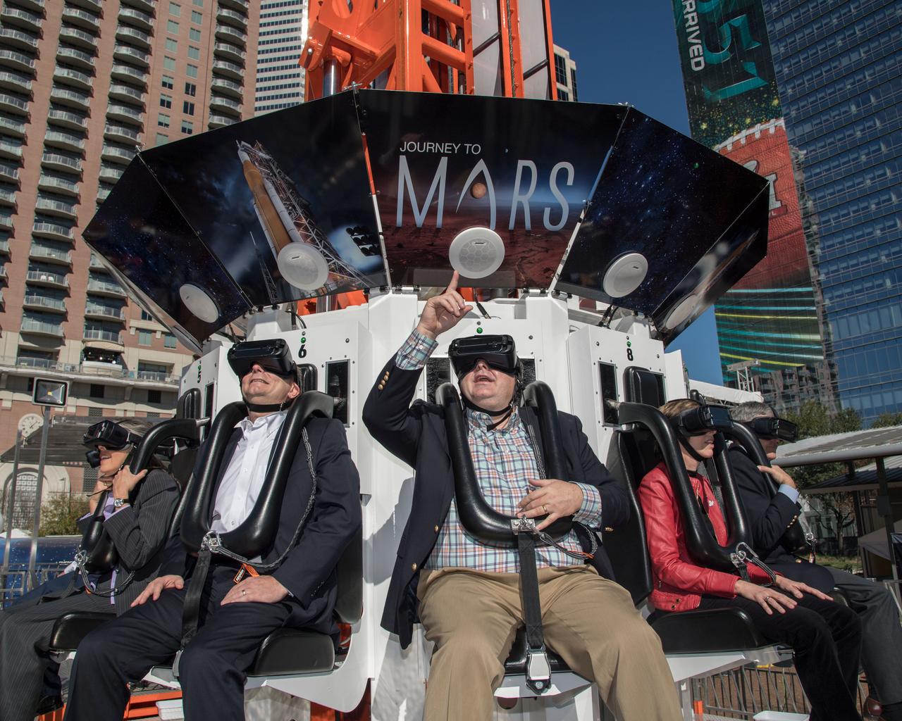 jsc2017e011382 (01/30/2017) --- Ready to take the Journey to Mars and back, a virtual reality experience at the Houston Texas Super Bowl, the Kennedy Space Center Director Robert Cabana (far right), Johnson Space Center Director Ellen Ochoa, Marshal Space Flight Center Director Todd May and the Orion Program Manager Mark Kirasich have been fitted with virtual headsets and are ready for the flight to begin. The Orion capsule will rise high above, some 90 feet, then drop suddenly to match and enhance the reality experience. The ride is part of the NASA Future Flight experience at the Super Bowl events in the Houston’s Discovery Green. NASA PHOTOGRAPHER: Bill Stafford