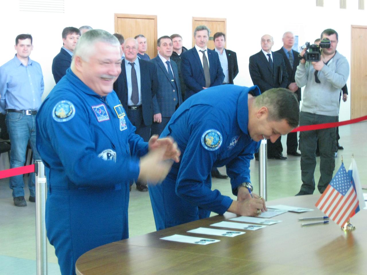 jsc2017e038546 (March 30, 2017) --- At the Gagarin Cosmonaut Training Center in Star City, Russia, Expedition 51 crewmember Fyodor Yurchikhin of the Russian Federal Space Agency (Roscosmos, left) applauds as his crewmate, Jack Fischer of NASA (right) signs in March 30 for the start of final crew qualification exams. They will launch April 20 on the Soyuz MS-04 spacecraft from the Baikonur Cosmodrome in Kazakhstan for a four and a half month mission on the International Space Station. Credit: NASA/Rob Navias