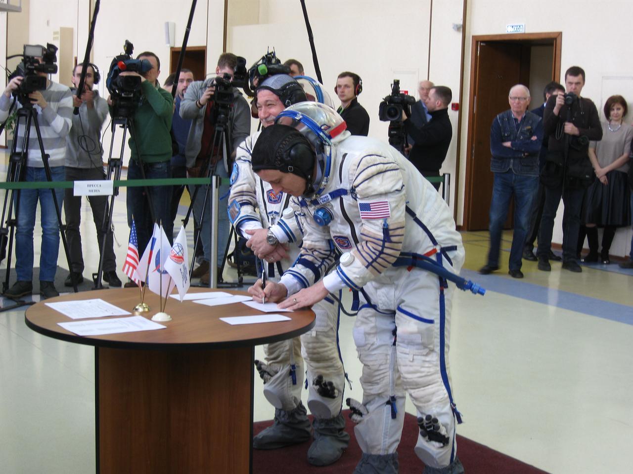 jsc2017e038909 (03/31/2017) --- At the Gagarin Cosmonaut Training Center in Star City, Russia, Expedition 51 crewmember Fyodor Yurchikhin of the Russian Federal Space Agency (Roscosmos, left) smiles as his crew mate, Jack Fischer of NASA (right) signs in March 31 for the second of two days of of final qualification exams. Yurchikhin and Fischer will launch April 20 on the Soyuz MS-04 spacecraft from the Baikonur Cosmodrome in Kazakhstan for a four and a half month mission on the International Space Station. Expedition 51. Photo: Rob Navias/NASA.