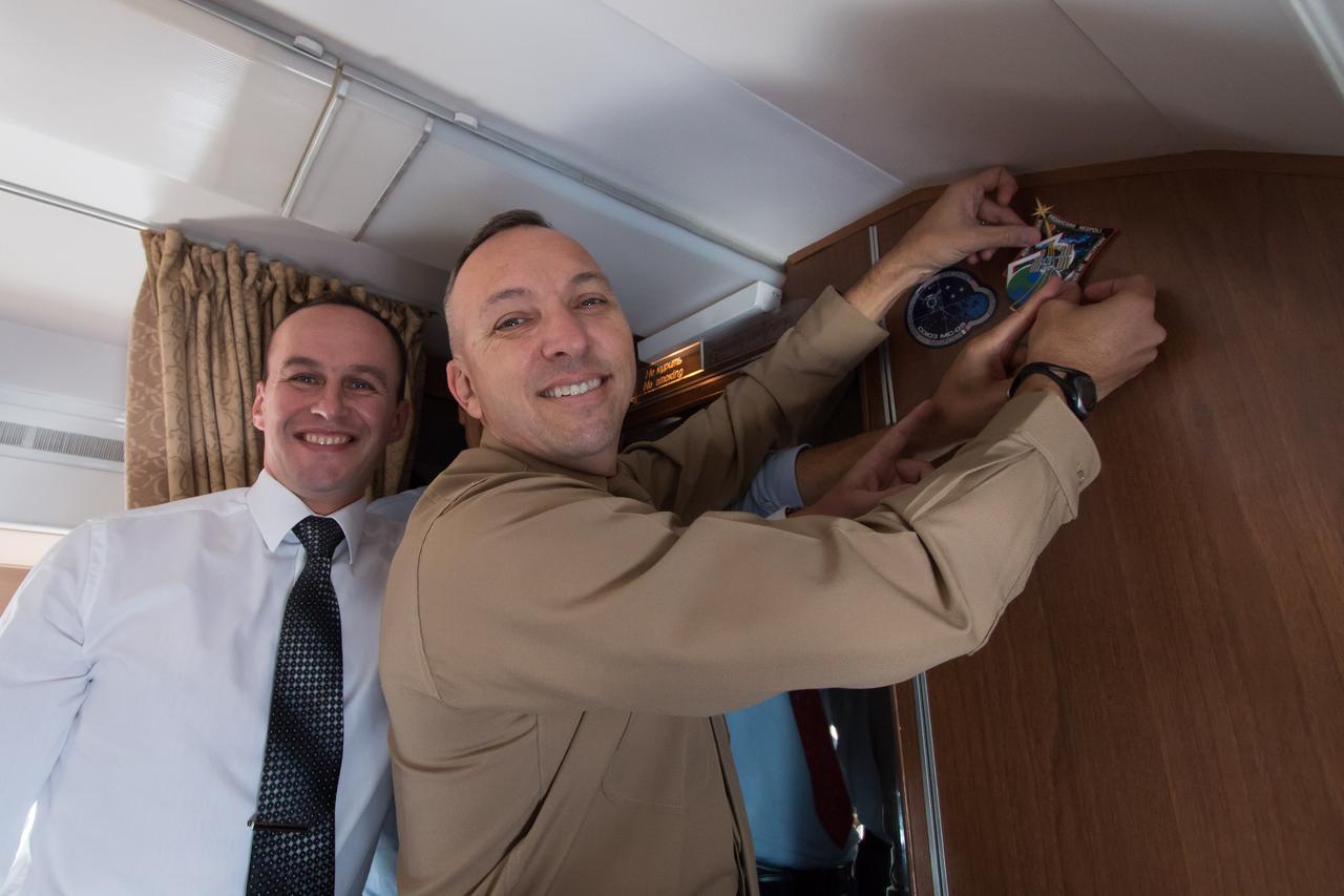 jsc2017e095961 (July 16, 2017) --- Aboard a Gagarin Cosmonaut Training Center aircraft en route to their launch site at the Baikonur Cosmodrome in Kazakhstan, Expedition 52-53 Flight Engineer Randy Bresnik of NASA (right), with the help of crewmate Sergey Ryazanskiy of the Russian Federal Space Agency (Roscosmos, left), affixes stickers bearing the Soyuz and Expedition 53 mission insignias to the wall of the plane’s cabin July 16 in a traditional ceremony. Bresnik, Ryazanskiy and Paolo Nespoli of the European Space Agency will launch July 28 from Baikonur on the Soyuz MS-05 spacecraft for a five-month mission on the International Space Station. Credit: NASA/Victor Zelentsov