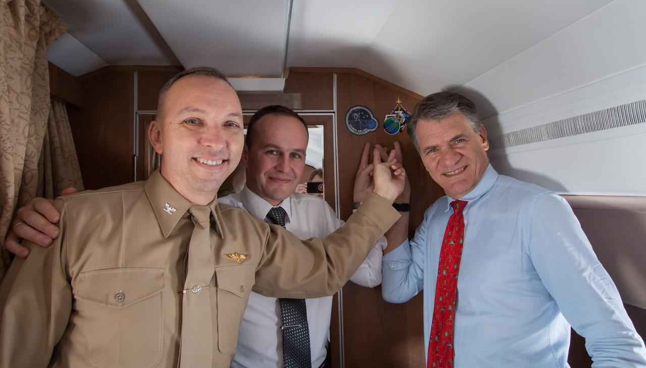 jsc2017e095962 (July 16, 2017) --- Aboard a Gagarin Cosmonaut Training Center aircraft en route to their launch site at the Baikonur Cosmodrome in Kazakhstan, Expedition 52-53 Flight Engineers Randy Bresnik of NASA (left), Sergey Ryazanskiy of the Russian Federal Space Agency (Roscosmos, center) and Paolo Nespoli of the European Space Agency (right) point to the stickers bearing the Soyuz and Expedition 53 mission insignias that they affixed to the wall of the plane’s cabin July 16 in a traditional ceremony. Bresnik, Ryazanskiy Nespoli will launch July 28 from Baikonur on the Soyuz MS-05 spacecraft for a five-month mission on the International Space Station. Credit: NASA/Victor Zelentsov