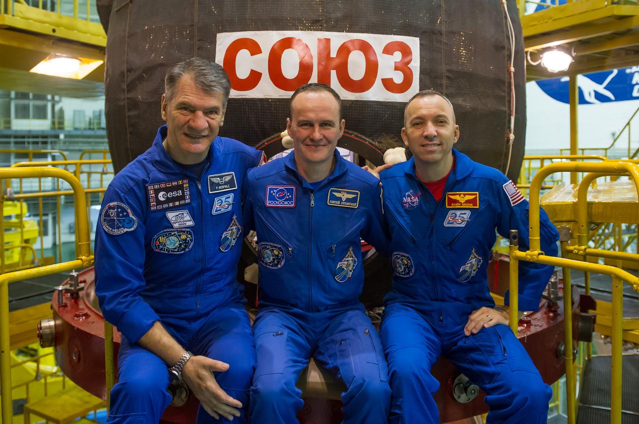 jsc2017e096662 (July 17, 2017) --- In the Integration Facility at the Baikonur Cosmodrome in Kazakhstan, Expedition 52-53 crewmembers Paolo Nespoli of the European Space Agency (left), Sergey Ryazanskiy of the Russian Federal Space Agency (Roscosmos, center) and Randy Bresnik of NASA (right) pose for pictures in front of their Soyuz MS-05 spacecraft July 17 as part of their fit check dress rehearsal activities. The trio will launch July 28 on the Soyuz MS-05 spacecraft for a five-month mission on the International Space Station. Credit: Andrey Shelepin/Gagarin Cosmonaut Training Center