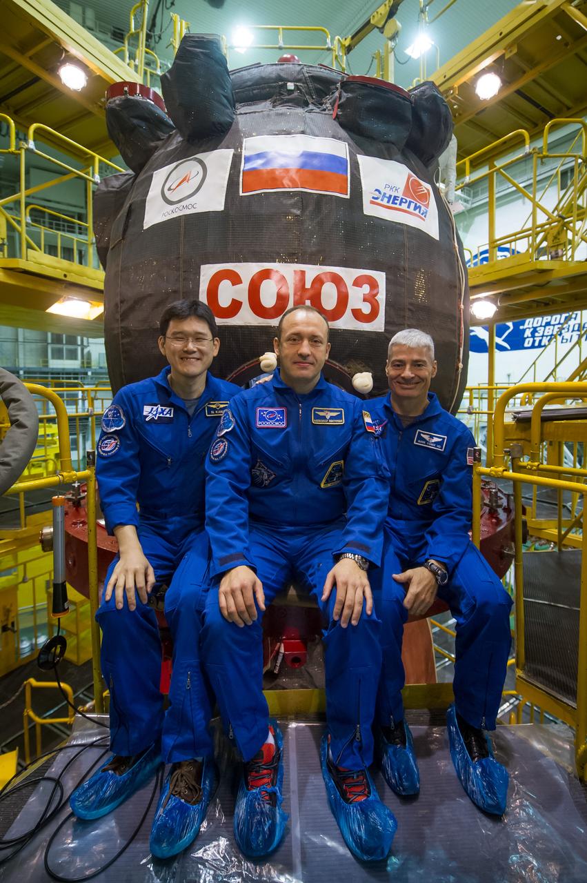 jsc2017e096667 (July 17, 2017) --- In the Integration Facility at the Baikonur Cosmodrome in Kazakhstan, Expedition 52-53 backup crewmembers Norishige Kanai of the Japan Aerospace Exploration Agency (JAXA, left), Alexander Misurkin of the Russian Federal Space Agency (Roscosmos, center) and Mark Vande Hei of NASA (right) pose for pictures in front of the Soyuz MS-05 spacecraft July 17 as part of their fit check dress rehearsal activities. The trio is serving as backups for Paolo Nespoli of the European Space Agency, Sergey Ryazanskiy of Roscosmos and Randy Bresnik of NASA, who will launch July 28 on the Soyuz MS-05 spacecraft for a five-month mission on the International Space Station. Credit: Andrey Shelepin/Gagarin Cosmonaut Training Center