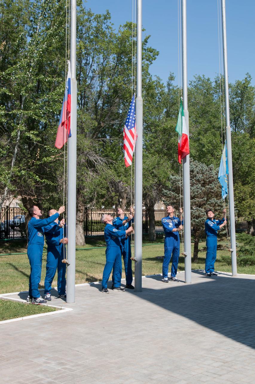 jsc2017e100896 (July 18, 2017) --- At the Cosmonaut Hotel crew quarters in Baikonur, Kazakhstan, the Expedition 52-53 prime and backup crewmembers raised the flags of the U.S., Russia, Italy and Kazakhstan July 18 during traditional pre-launch ceremonies. From left to right are Sergey Ryazanskiy and Alexander Misurkin of the Russian Federal Space Agency (Roscosmos) raising the Russian flag, Mark Vande Hei and Randy Bresnik of NASA raising the U.S. flag, Paolo Nespoli of the European Space Agency raising the flag of Italy and Norishige Kanai of the Japan Aerospace Exploration Agency (JAXA) raising the flag of Kazakhstan. Ryazanskiy, Bresnik and Nespoli will launch July 28 on the Soyuz MS-05 spacecraft from the Baikonur Cosmodrome for a five-month mission on the International Space Station. Credit: NASA/Victor Zelentsov