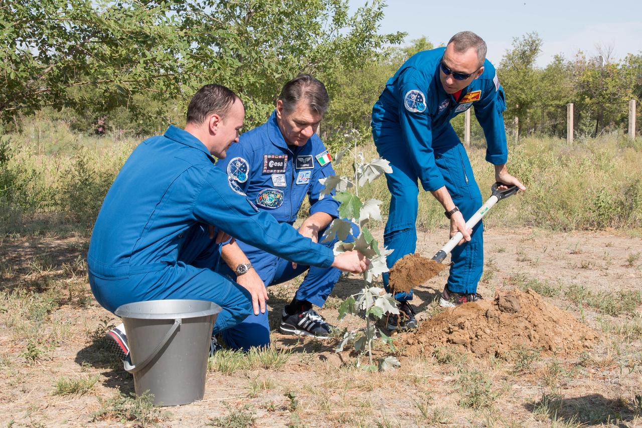 jsc2017e101932 (July 22, 2017) --- At the Cosmonaut Hotel crew quarters in Baikonur, Kazakhstan, Expedition 52-53 Flight Engineer Randy Bresnik (right) pitches in with a shovel full of dirt July 22 and he and his crewmates, Sergey Ryazanskiy of the Russian Federal Space Agency (Roscosmos, left) and Paolo Nespoli of the European Space Agency (center) plant a tree in Bresnik’s name in traditional pre-launch ceremonies. The trio will launch July 28 on the Soyuz MS-05 spacecraft from the Baikonur Cosmodrome for a five-month mission on the International Space Station. Credit: NASA/Victor Zelentsov
