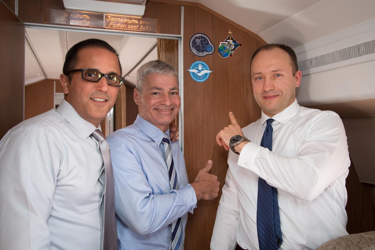 jsc2017e114747 (Sept. 6, 2017) --- Aboard the Gagarin Cosmonaut Training Center Aircraft en route from their training base to their launch site at the Baikonur Cosmodrome in Kazakhstan for final pre-launch training, Expedition 53-54 crewmembers Joe Acaba (left) and Mark Vande Hei (center) of NASA and Alexander Misurkin of Roscosmos (right) point to the stickers bearing their mission insignias Sept. 6. They will launch Sept. 13 on the Soyuz MS-06 spacecraft from the Baikonur Cosmodrome for a five and a half month mission on the International Space Station. Credit: NASA/Victor Zelentsov