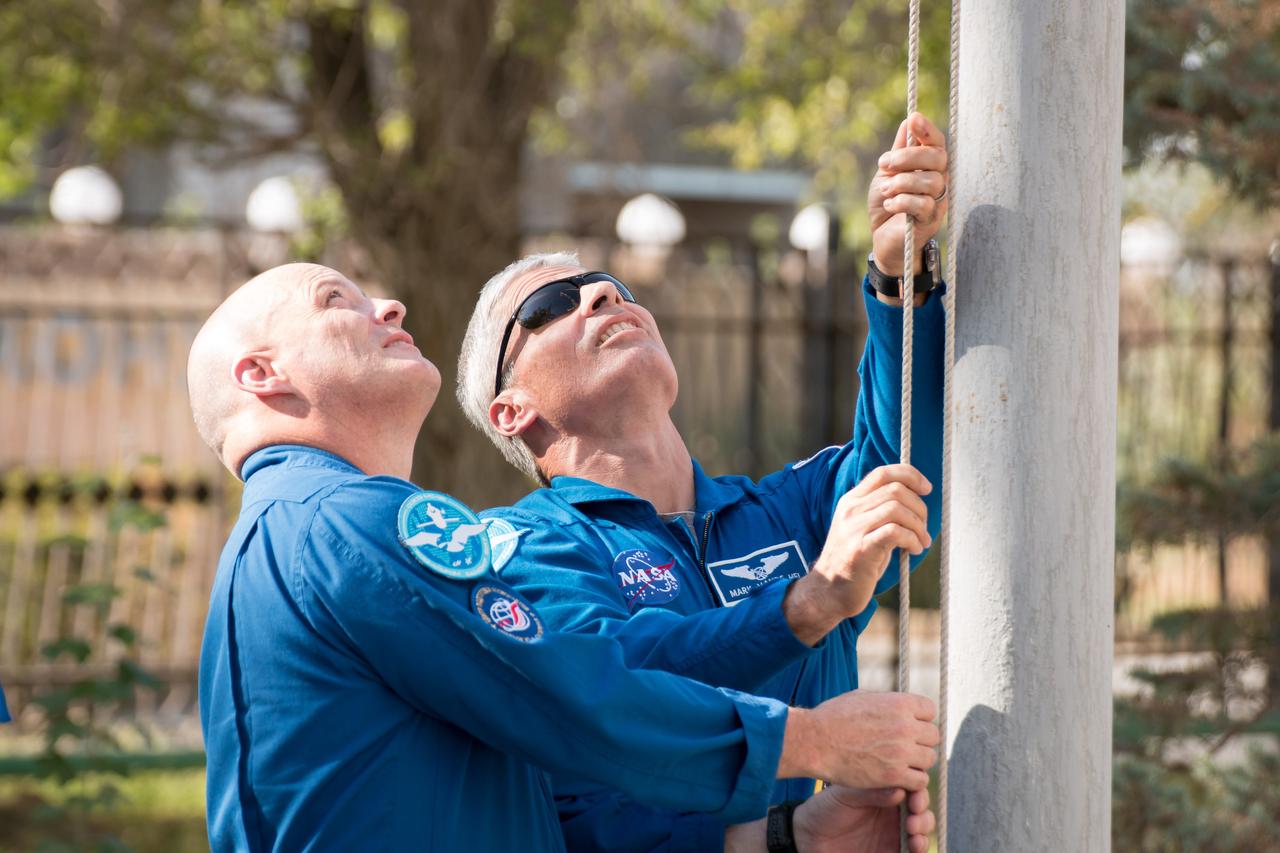 jsc2017e115138 (Sept. 7, 2017) --- At their Cosmonaut Hotel crew quarters in Baikonur, Kazakhstan, Expedition 53-54 backup and prime crewmembers Scott Tingle of NASA (left) and Mark Vande Hei of NASA (right) raise the United States flag Sept. 7 during traditional pre-launch ceremonies. Vande Hei, Joe Acaba of NASa and Alexander Misurkin of Roscosmos will launch Sept. 13 on the Soyuz MS-06 spacecraft for a five and a half month mission on the International Space Station. Credit: NASA/Victor Zelentsov